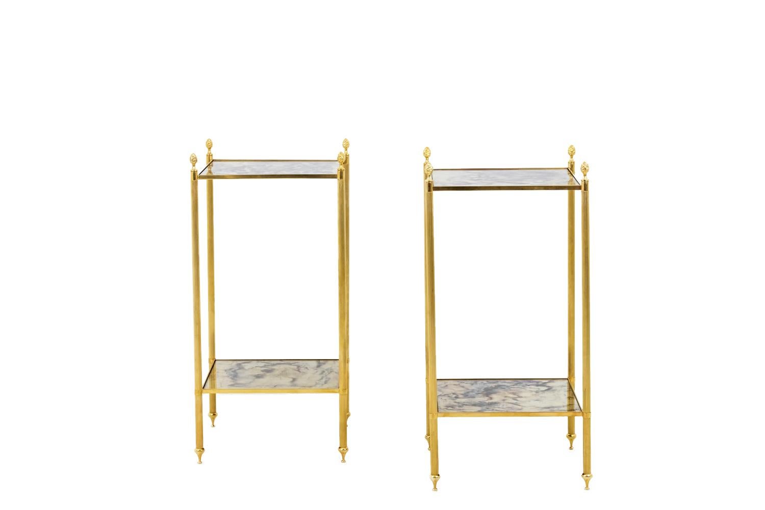 Maison Jansen, in the style of.

Pair of square end tables in gilt brass with two overlapped trays. Filleted column shape legs finishing by spinning top shape shoes and topped by pinecones.
Square oxidized mirror trays.

Work realized in the