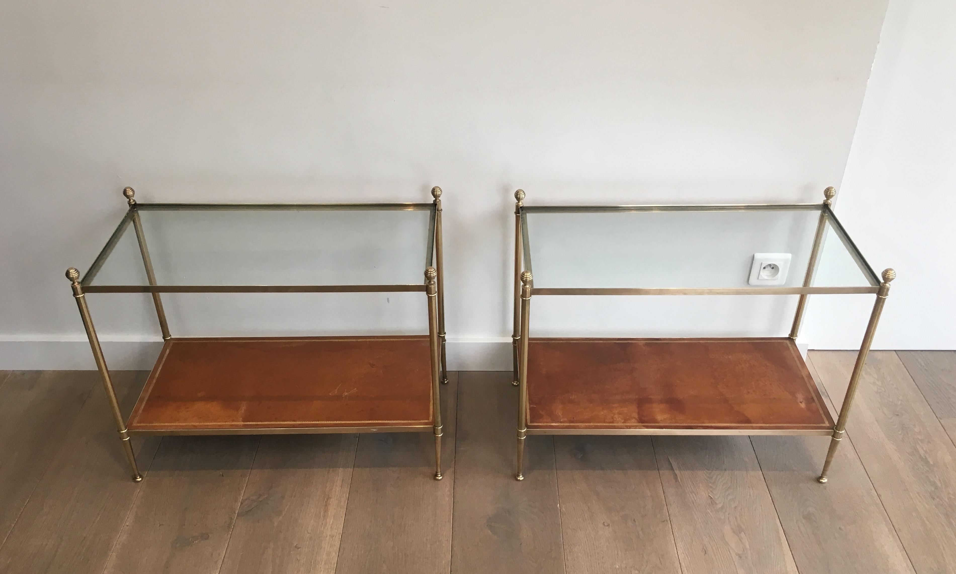 This rare pair of large neoclassical style side tables is made of brass with leather shelves on bottom and clear glass shelves on top. This is a very nice pair of end tables, very fine with very nice original brown golden iron leathers. These side