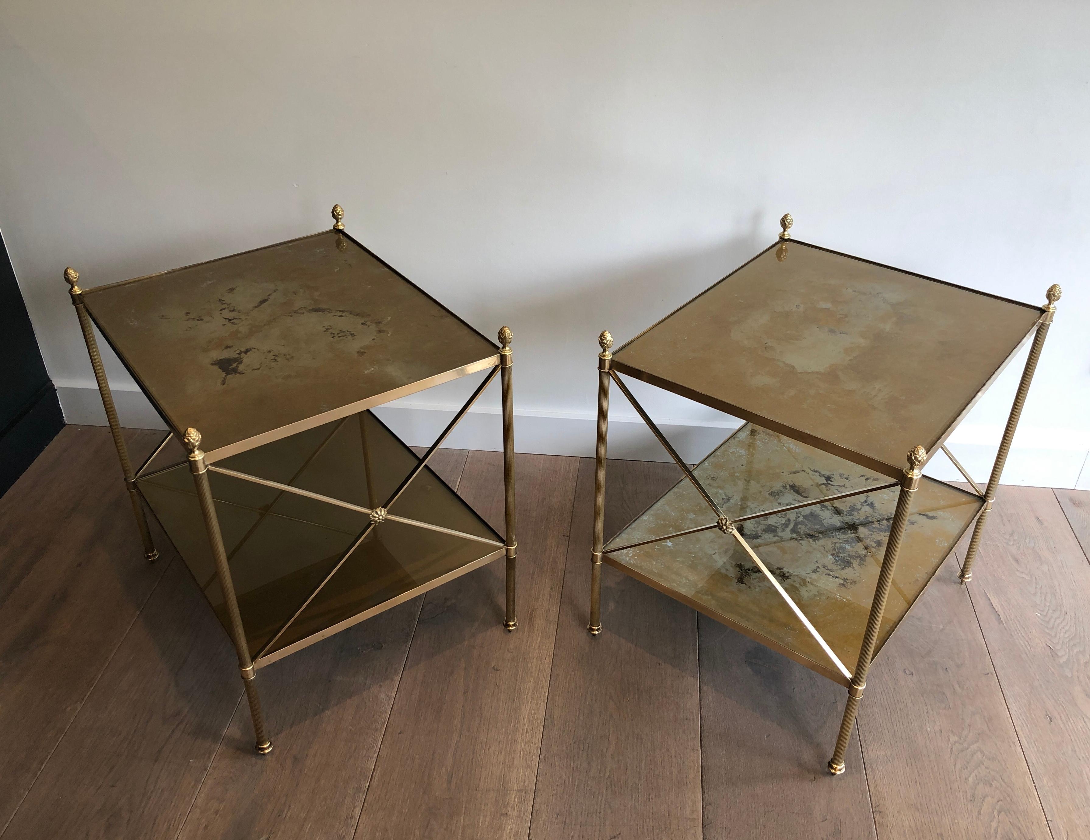 This beautiful pair of neoclassical style two-tiered side tables is all made of brass with eglomized gold glass shelves. This is a very nice and fine work typical of Maison Bagués with these delicate fluted legs, this fine gilt finials on each