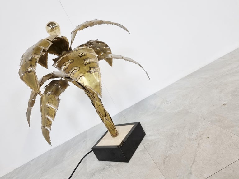 Beautiful torch cut brass palm tree table lamp by Maison Jansen.

This palm lamp has a top mounted light point.

Base is made from travertine and black lacquered wood.

Good original condition, tested and ready to use.

The lamp has a