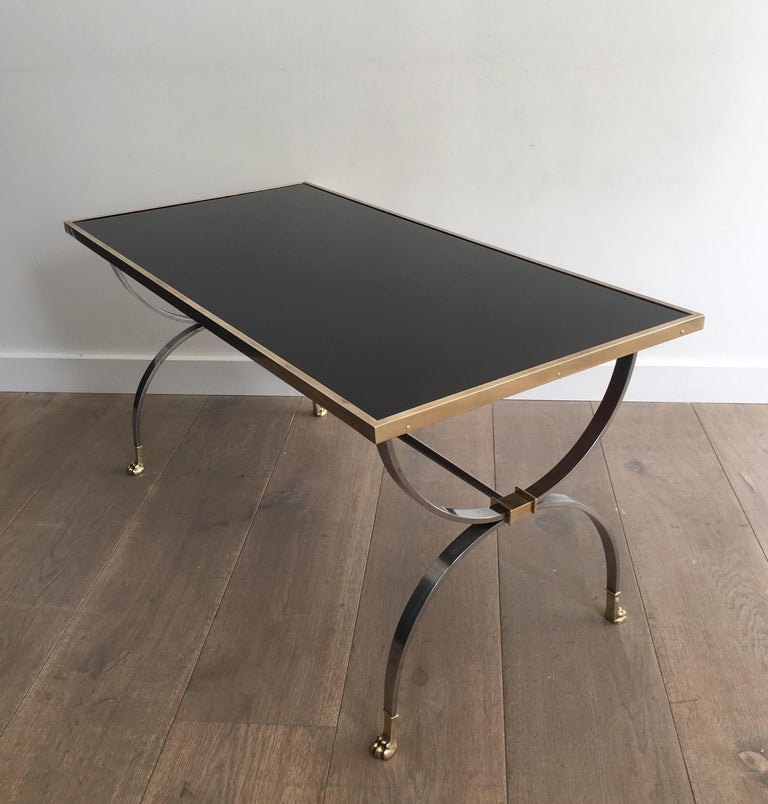 This rare and beautiful neoclassical style coffee table is made of brushed steel and brass with a black lacquered top. The legs are ended by bronze claw feet. This a work by famous French designer Maison Jansen, circa 1940.