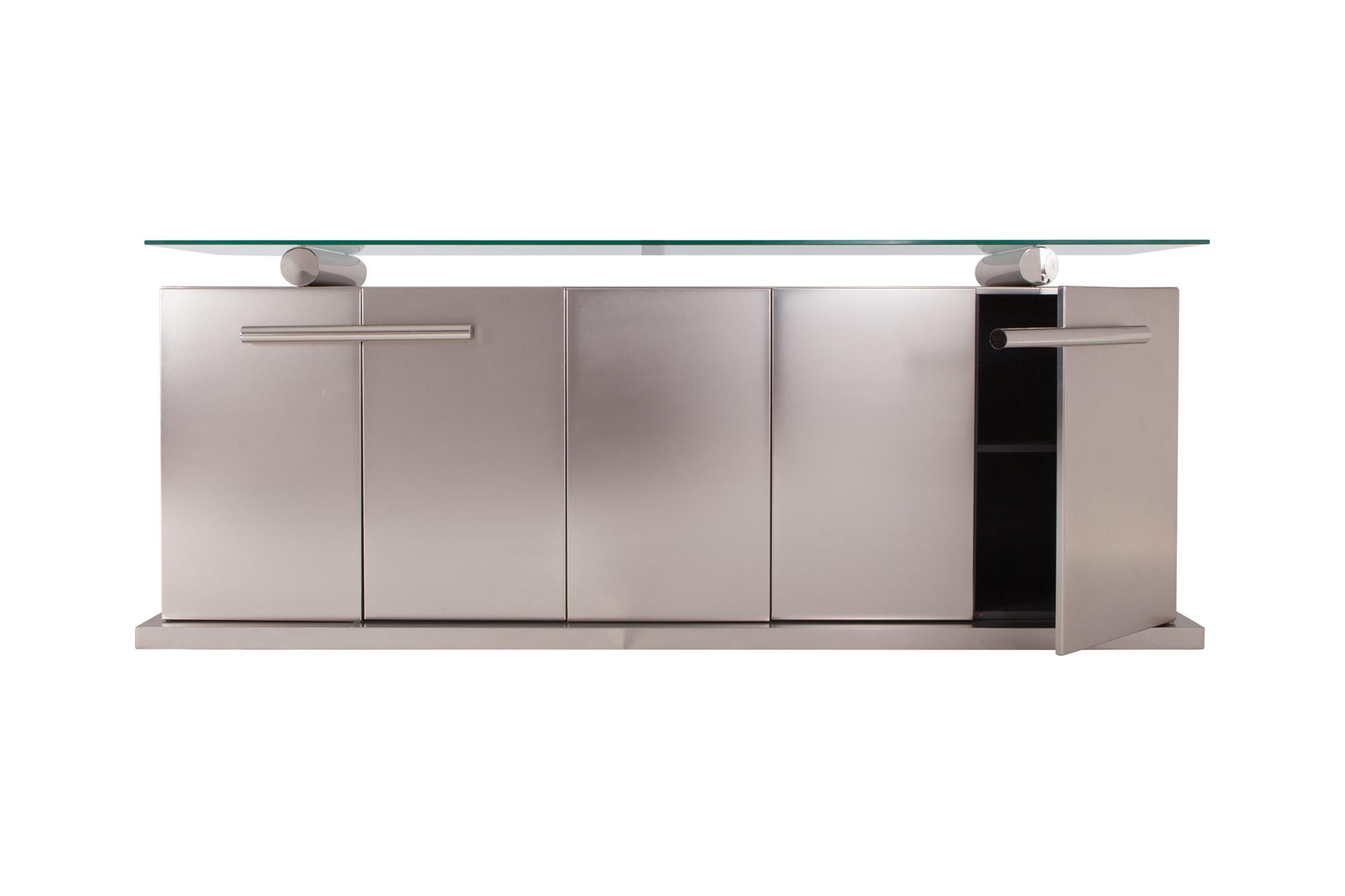 Hollywood regency style credenza in Brushed metal and chrome detailing.   

A thick floating glass top gives the unit a most royal presence. The four door sideboard is fitted with chrome fixtures and is in amazing condition.

 In the style of Maison