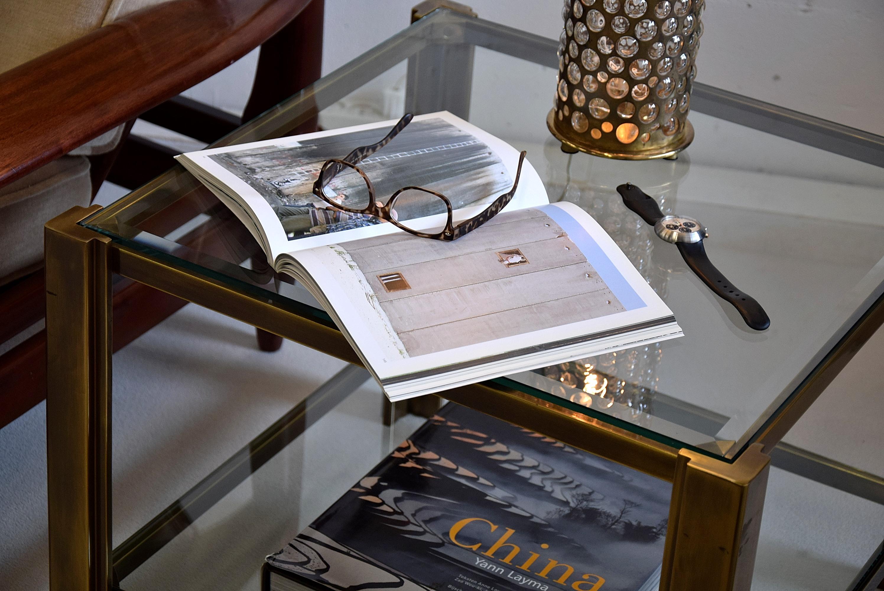 Stylish Hollywood Regency solid brass Maison Jansen side tables produced in France in the late 1970's. This sophisticated pair of side tables is in very good condition but obviously have signs of wear. Minor scratches and one of the glass plates