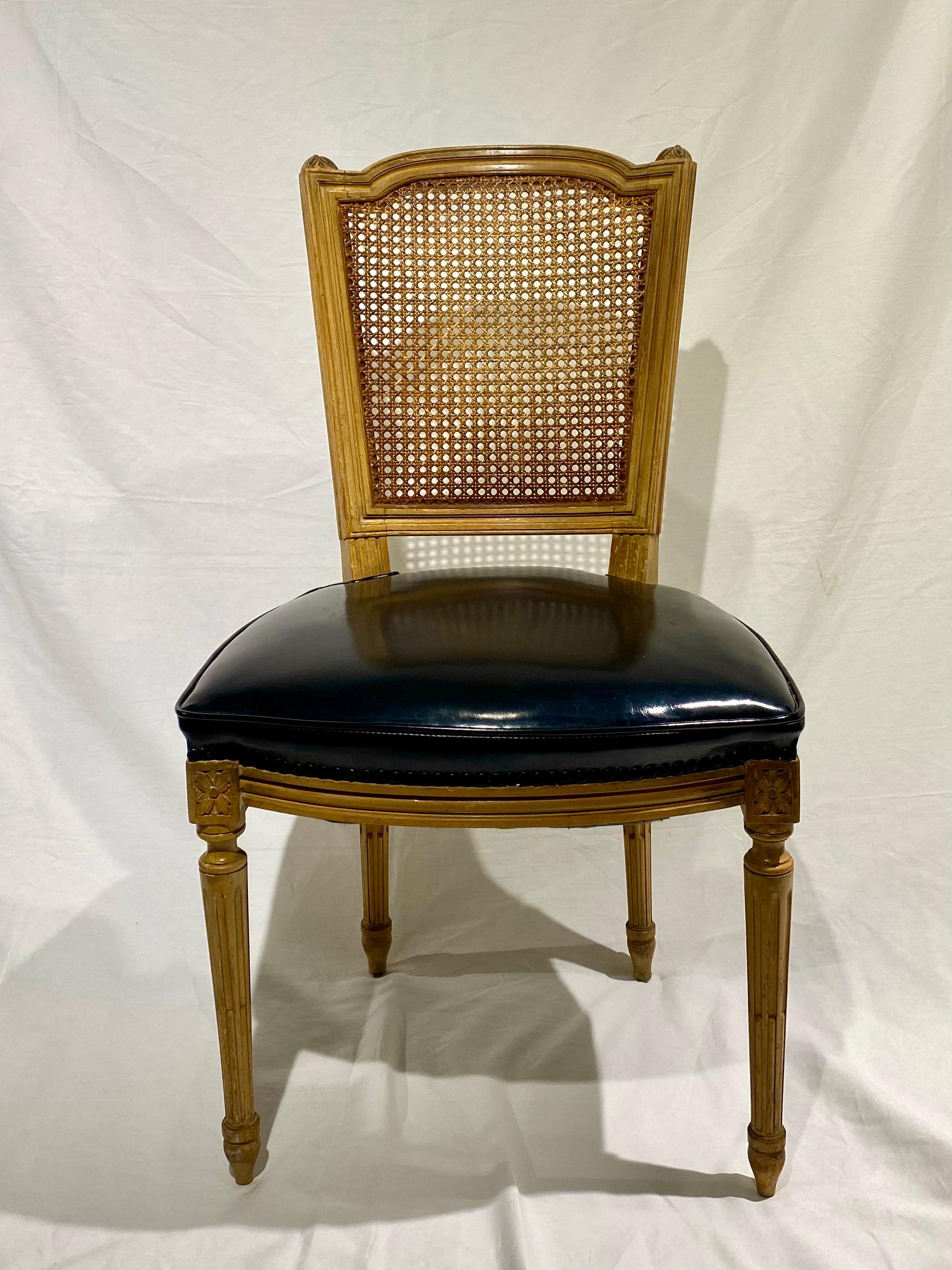 Set of four stamped Maison Jansen French patinated cane back chairs in the classic style of Louis XVI, with black upholstered patent seats. Mid-Century Modern, Hollywood Regency style. Stamped Jansen.
  