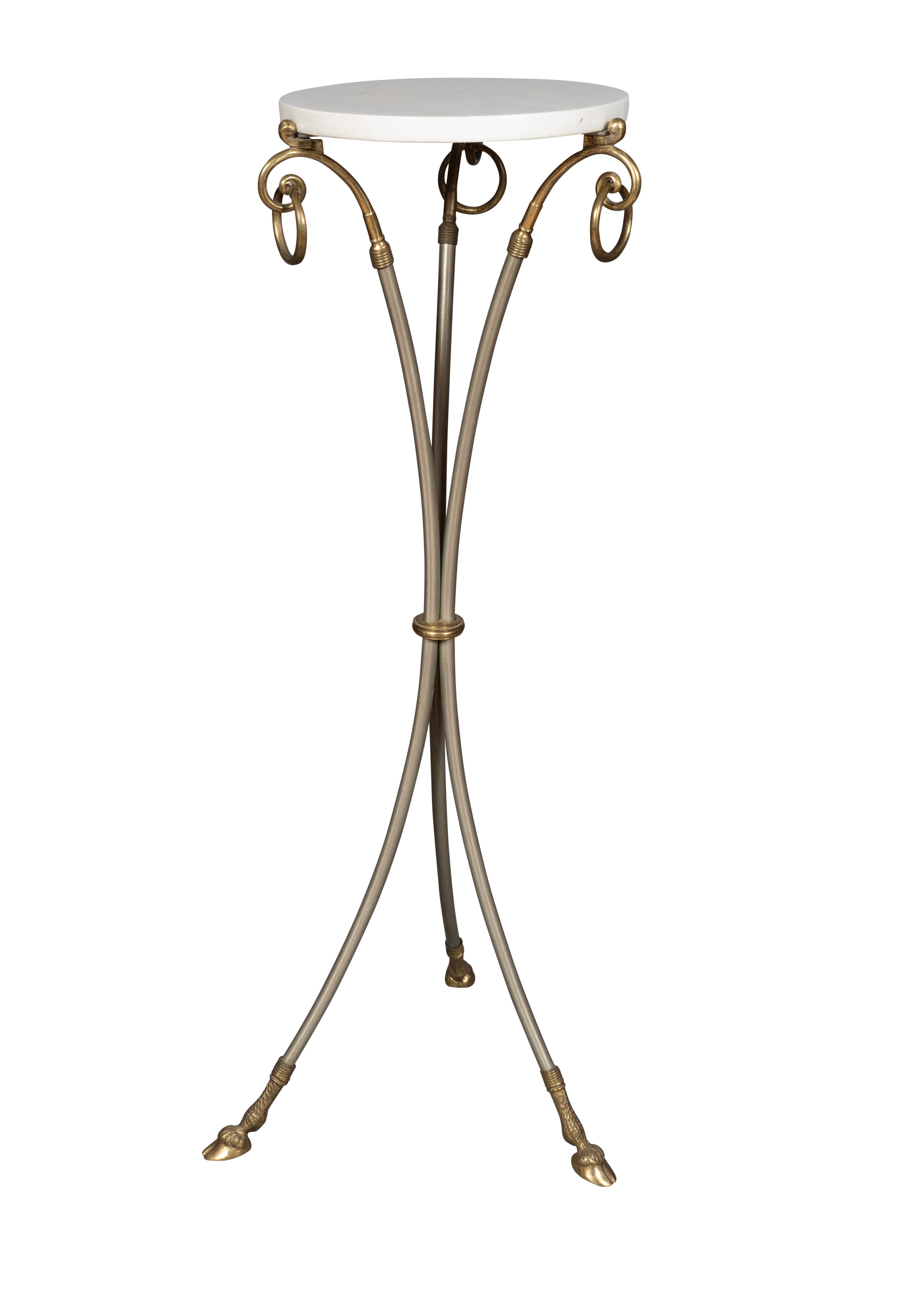 Circular white marble top that is removable for transport and seated on a steel ring mounted to three volutes with rings, the whole gathered at the waist and ending on splayed legs with hoof feet. 