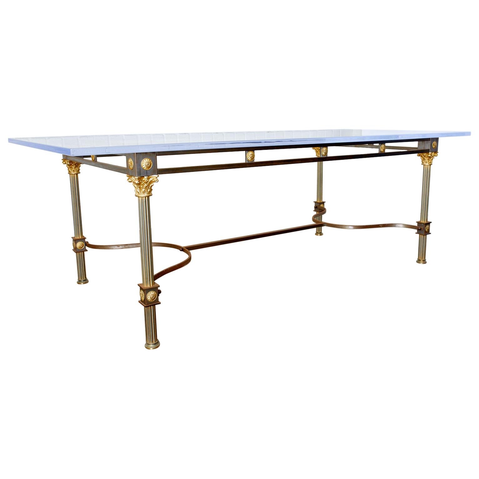 Dramatic steel and brass dining table by Maison Jansen with a later lucite top. Features Corinthian style capitols with fluted columns on each corner supporting the top. The columns are conjoined by gracefully curving stretchers on bottom. The apron