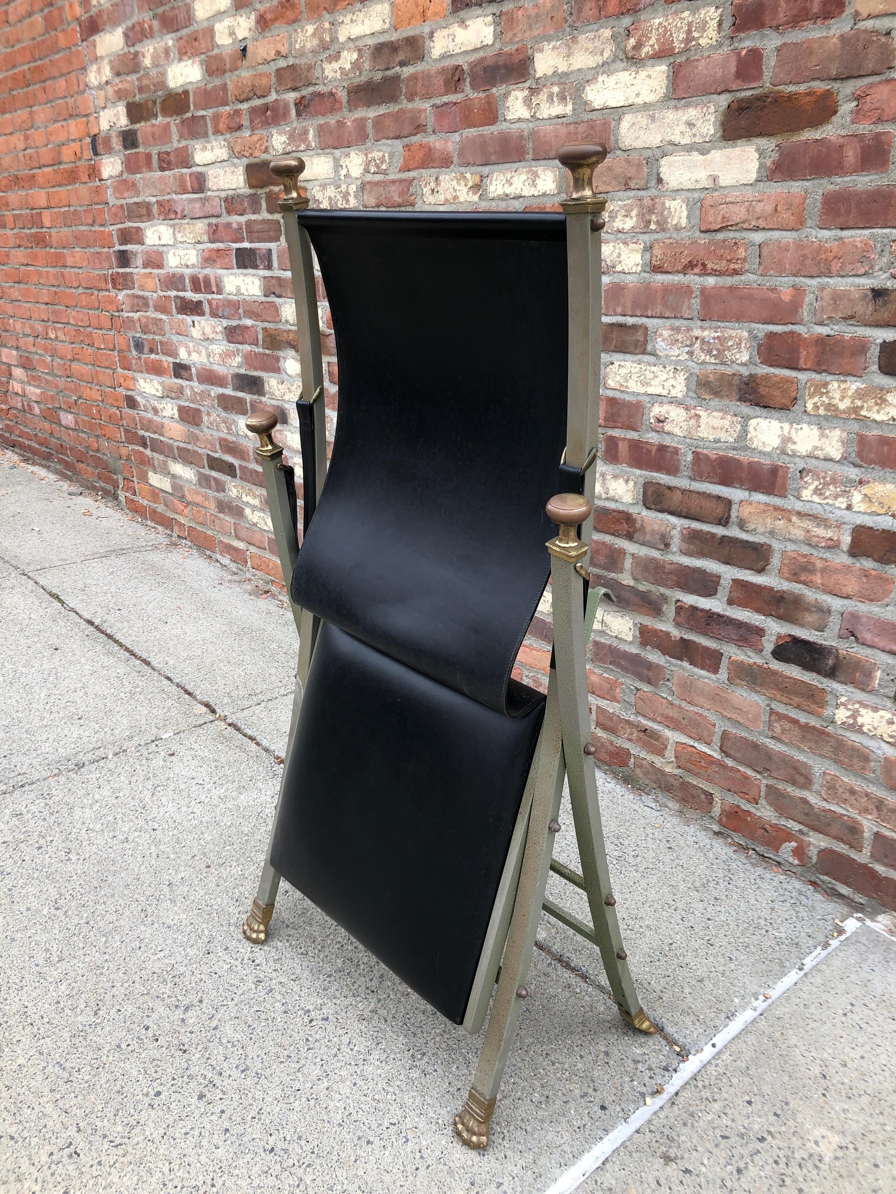 Chic folding chair with neoclassical styling. Leather seat and arm straps, with solid flat bar steel frame and bronze paw feet and knob handles. Produced in Italy for Maison Jansen.