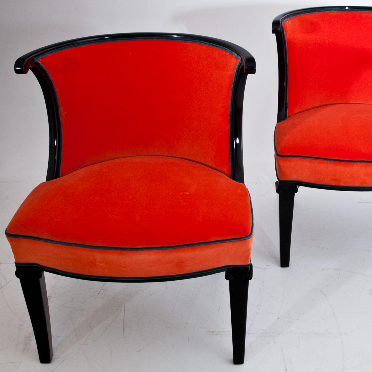 Pair of armchairs with rounded backrests and an ebonized frame, the front legs with volute capitals and the rear legs are slightly curved. The chairs were reupholstered with a high quality orange fabric with blue piping. 

Seat depth: 45 cm.