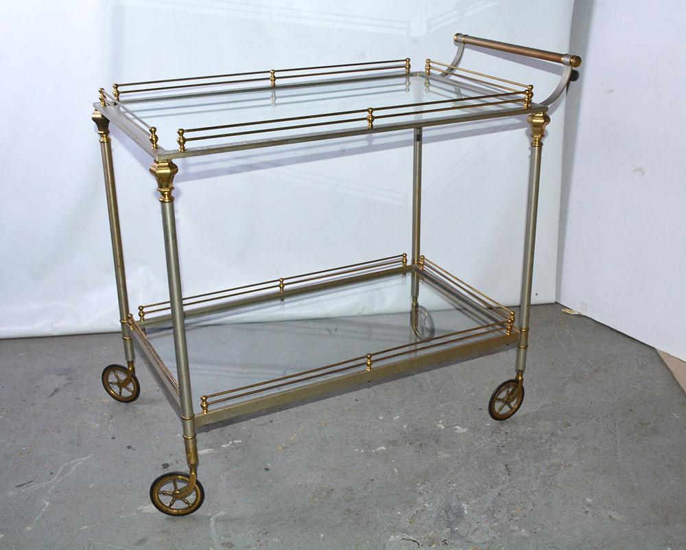 This stylish vintage brushed metal bar cart, created in the Maison Jansen neoclassical style featuring two glass tiers with gallery surround fitted with 4 small casters. Trolley or serving table.
Height between glasses: 20.25
