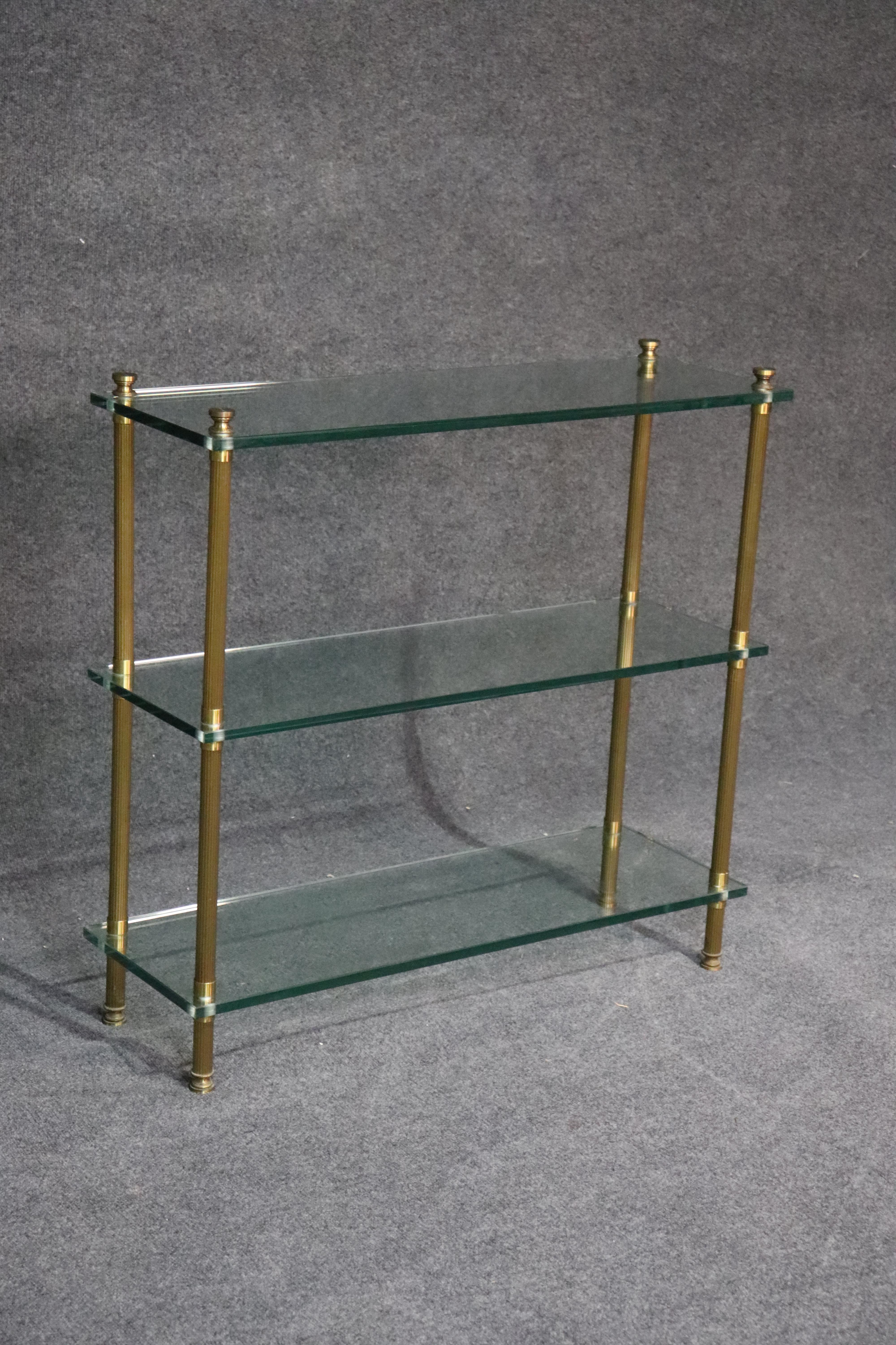 This is a gorgeous fluted brass and extra thick glass three tier console table or etagere, most likely made by Jansen, but unsigned. The quality is superb and the materials are heavy, and beautifully constructed. This can be used in a hallway or