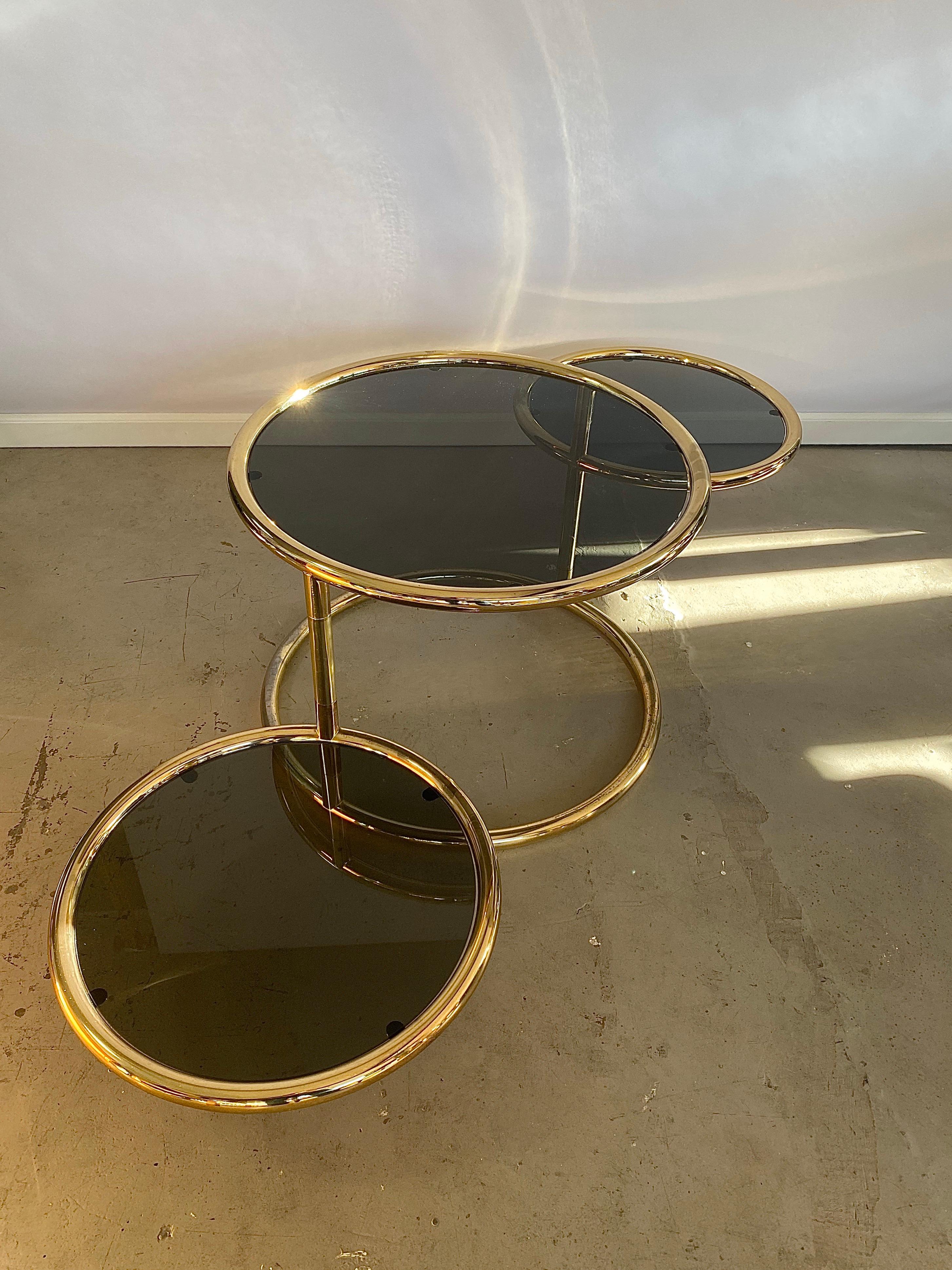Very rare to find shiny brass with smoked dark tinted glass 3-tier coffee table or side table. The upper glass top level is in a fixed position, the two lower level tops can turn a 360 degrees, you'll never have to move the table as a whole when it