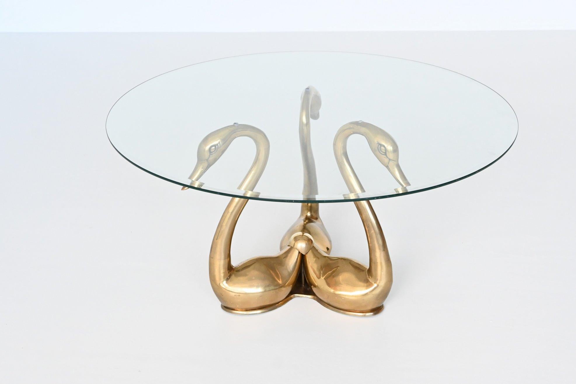 Beautiful and elegant swan shaped coffee or side table designed and manufactured in the style of Maison Jansen, France 1970. This table features a base of three brass swans that supports a thick round glass top. It is in very good original condition
