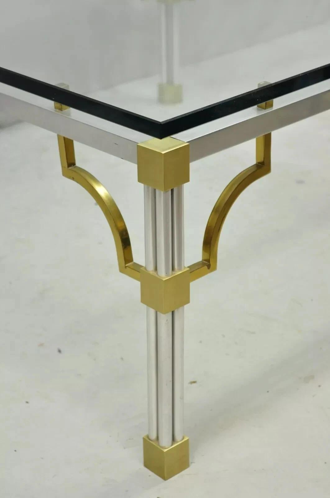 Table basse vintage en aluminium brossé, laiton, clé grecque, verre ajouré, de style Maison Jansen. Cet article présente un épais plateau en verre flottant, un cadre en aluminium moulé, des accents en laiton, des coins chantournés, un très bel