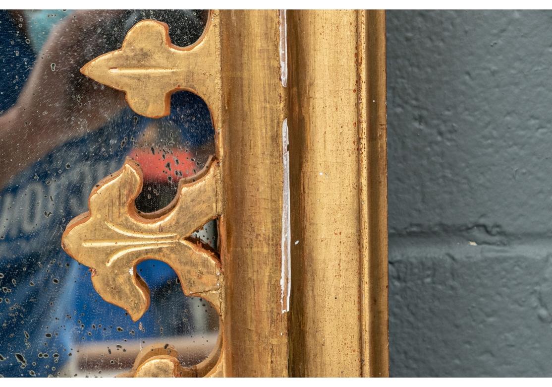 Ein eleganter und sehr dekorativer Hollywood Regency Spiegel aus vergoldetem Holz im Stil von Maison Jansen zur Restaurierung mit Schäden am Holz, der Vergoldung und einigen alten Reparaturen. Zweiteiliger Spiegel mit aufwendig geschnitzter