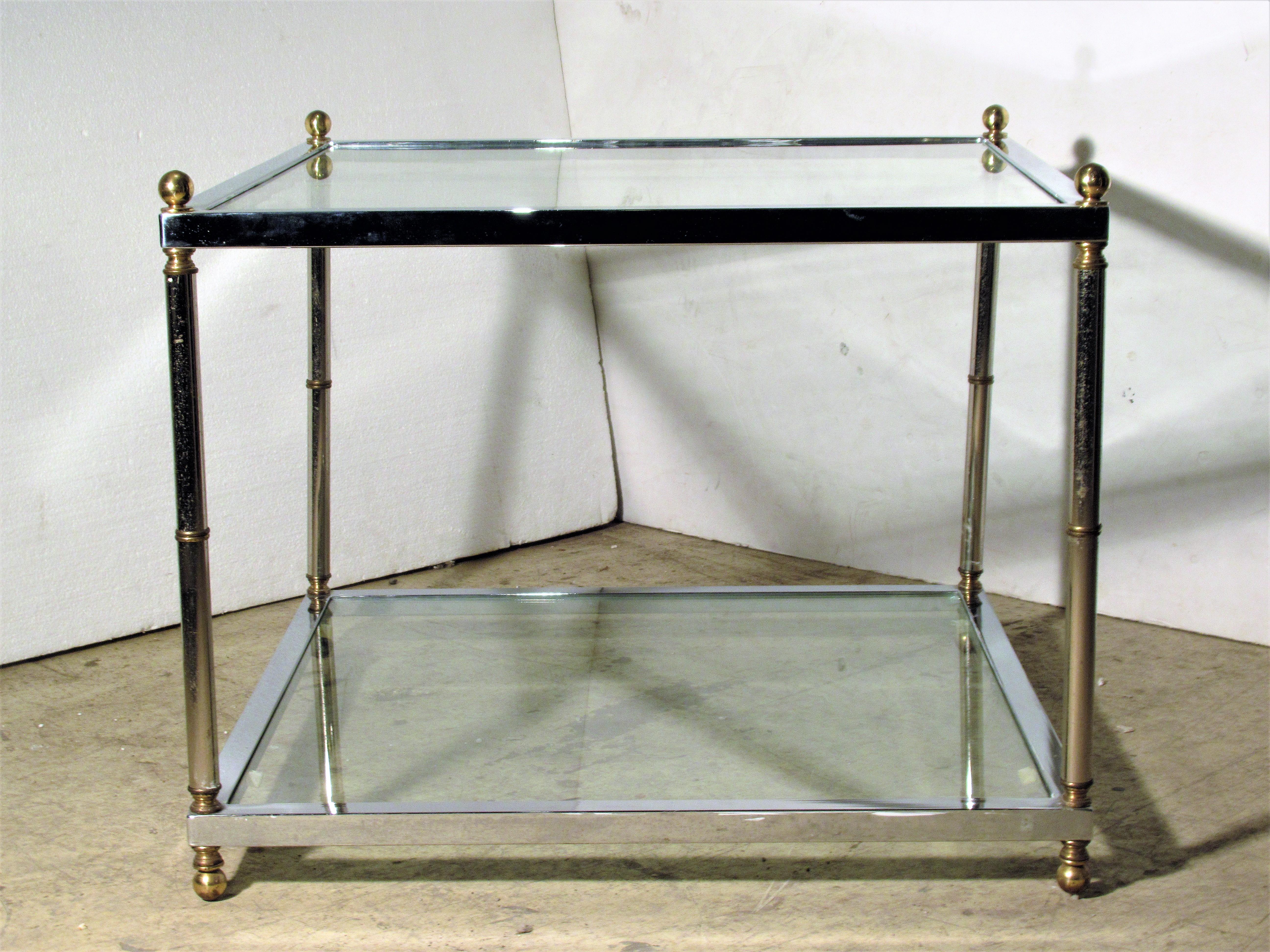 A good quality square two tier (glass top / lower glass shelf) chromed steel table with brass ball finials, brass ball feet and brass banding. In the style of Maison Jansen, circa 1970.