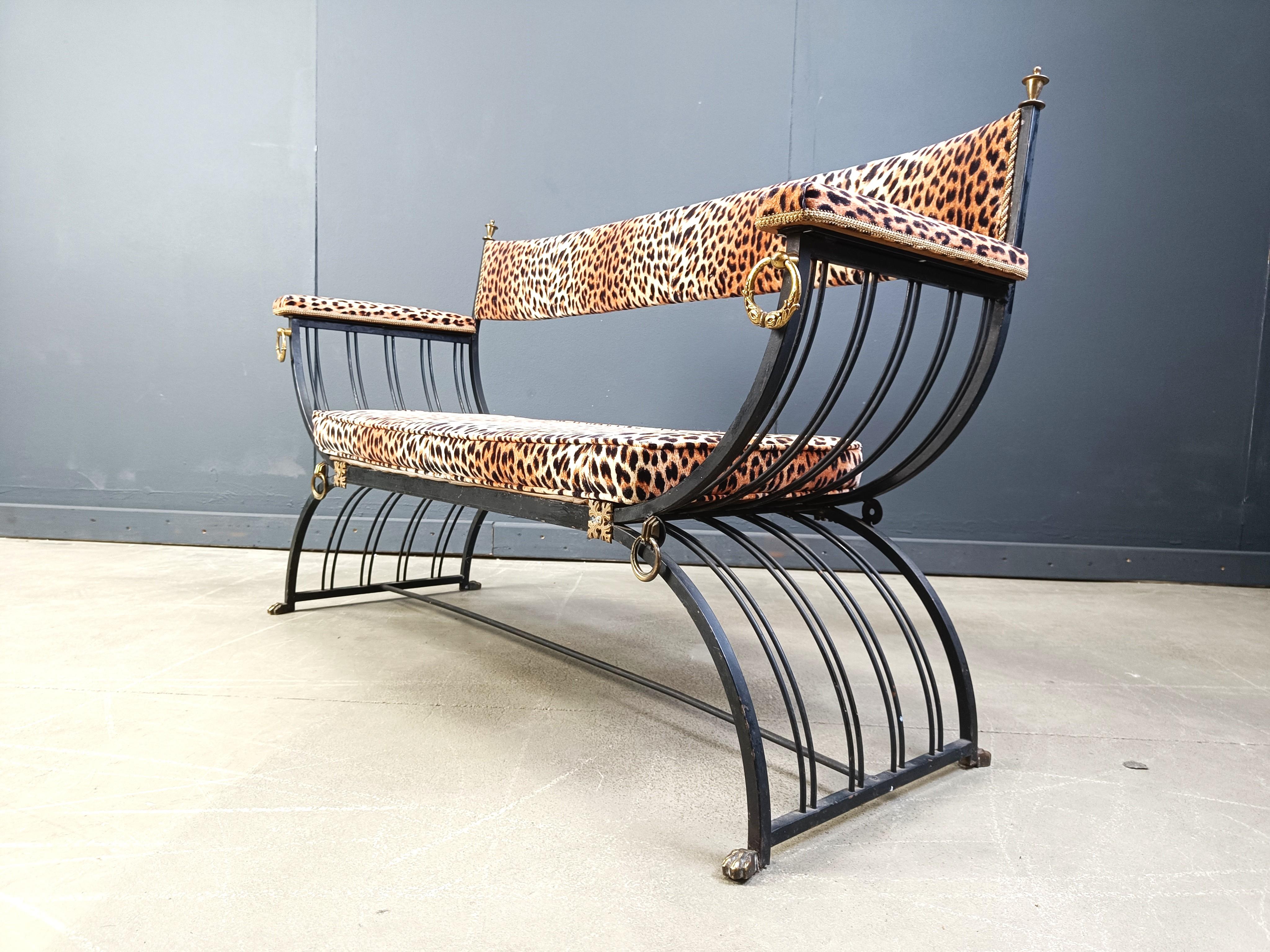 Fantastic Hollywood regency 'curule' bench made from black wrought iron and with brass details. 

Brass claw feet and rings. 

Armrests backrest and seat upholstered in leopard printed fabric.

Beautiful decorative bench.

1960s - France

Height: