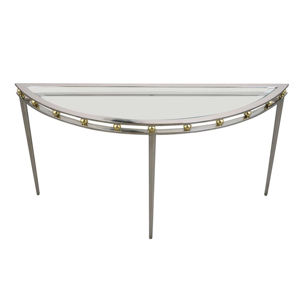 This 1970s Regency Demilune Console table features a chrome and brass base with a glass top. The half-circle table is accented by brass balls separating the legs and the glass top. The glass top is 1/4 inch thick with a flat polish. This Vintage
