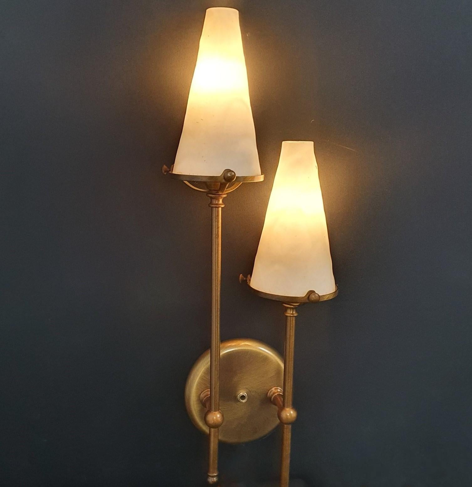A tall Art Deco two-arm sconce wall light in style of Maison Jansen, France, 1955-1959. Very elegant design made of bronzed brass with two conical glass shades. It takes 2 Edison E14 candelabra screw bulbs. LED bulbs can also be used. In very good