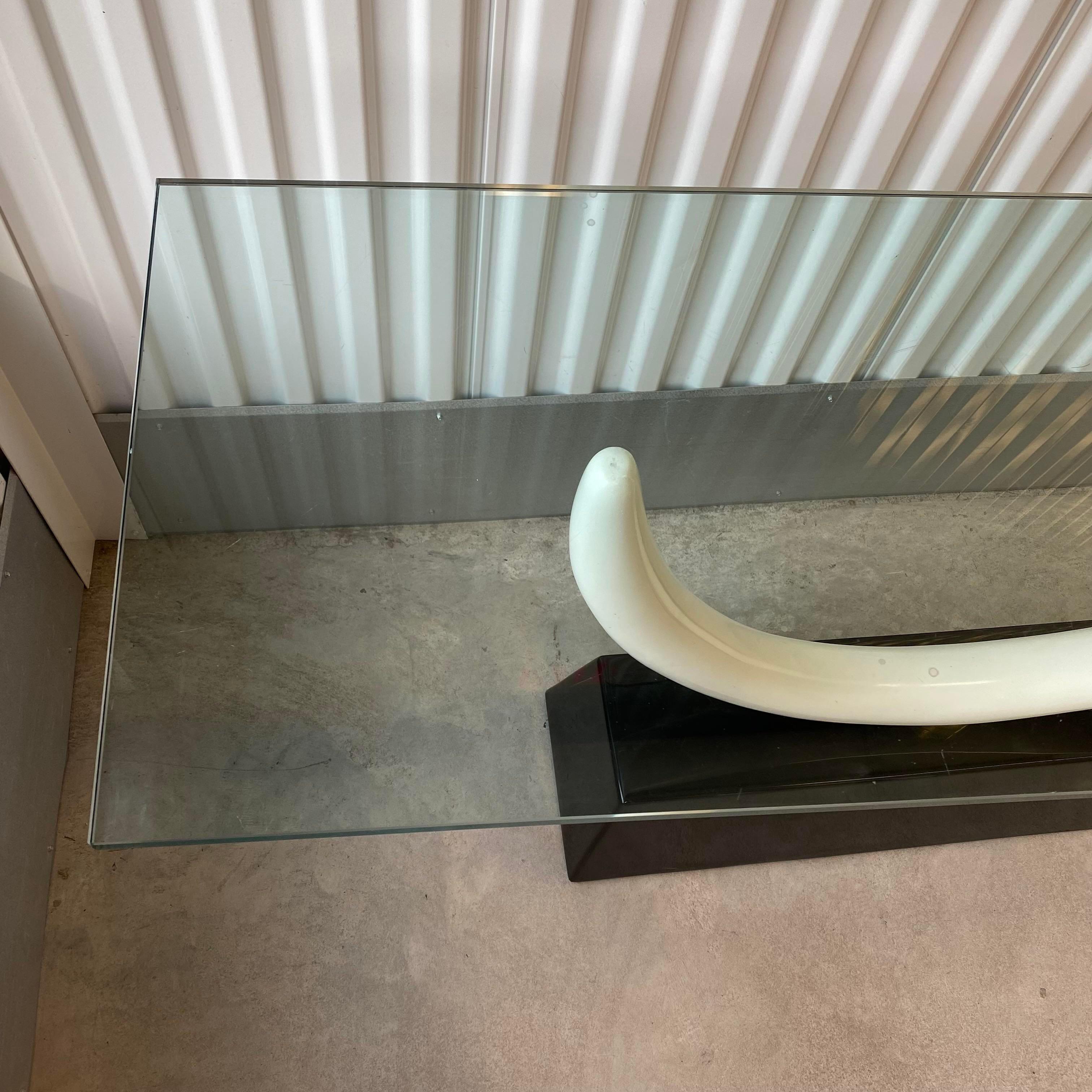 After Maison Jansen console table with a faux ivory tusk mounted on a black lacquered base. Brass accents attach the tusk to the base and the top brass piece holds the glass in place. The glass is pierced and the brass piece that sits on top of the
