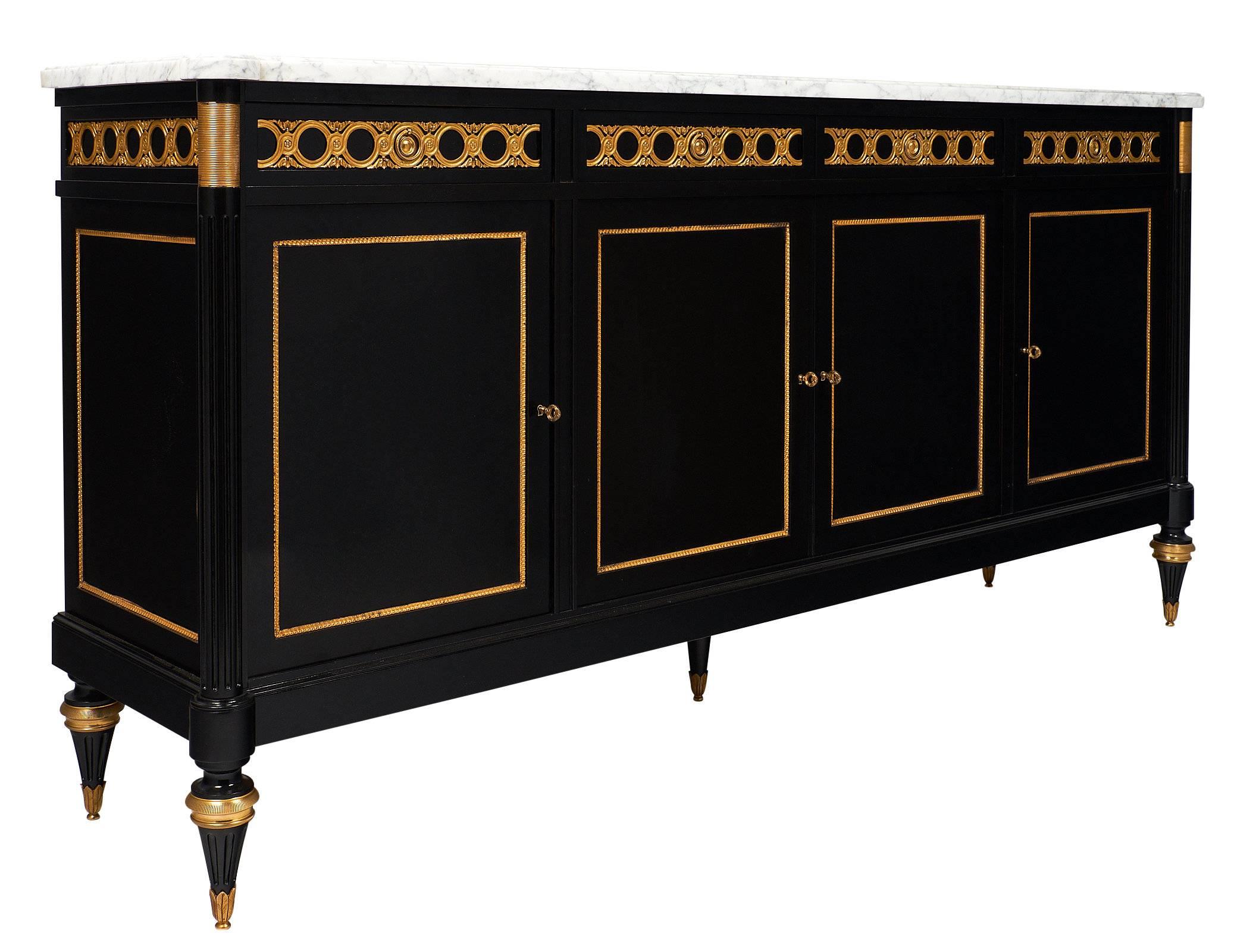 A sumptuous buffet or enfilade in the manner of iconic Parisian design firm Maison Jansen. This stunning credenza features four doors, four drawers, a white lightly veined Carrara marble top, and rests on fluted and tapered legs. The buffet boasts