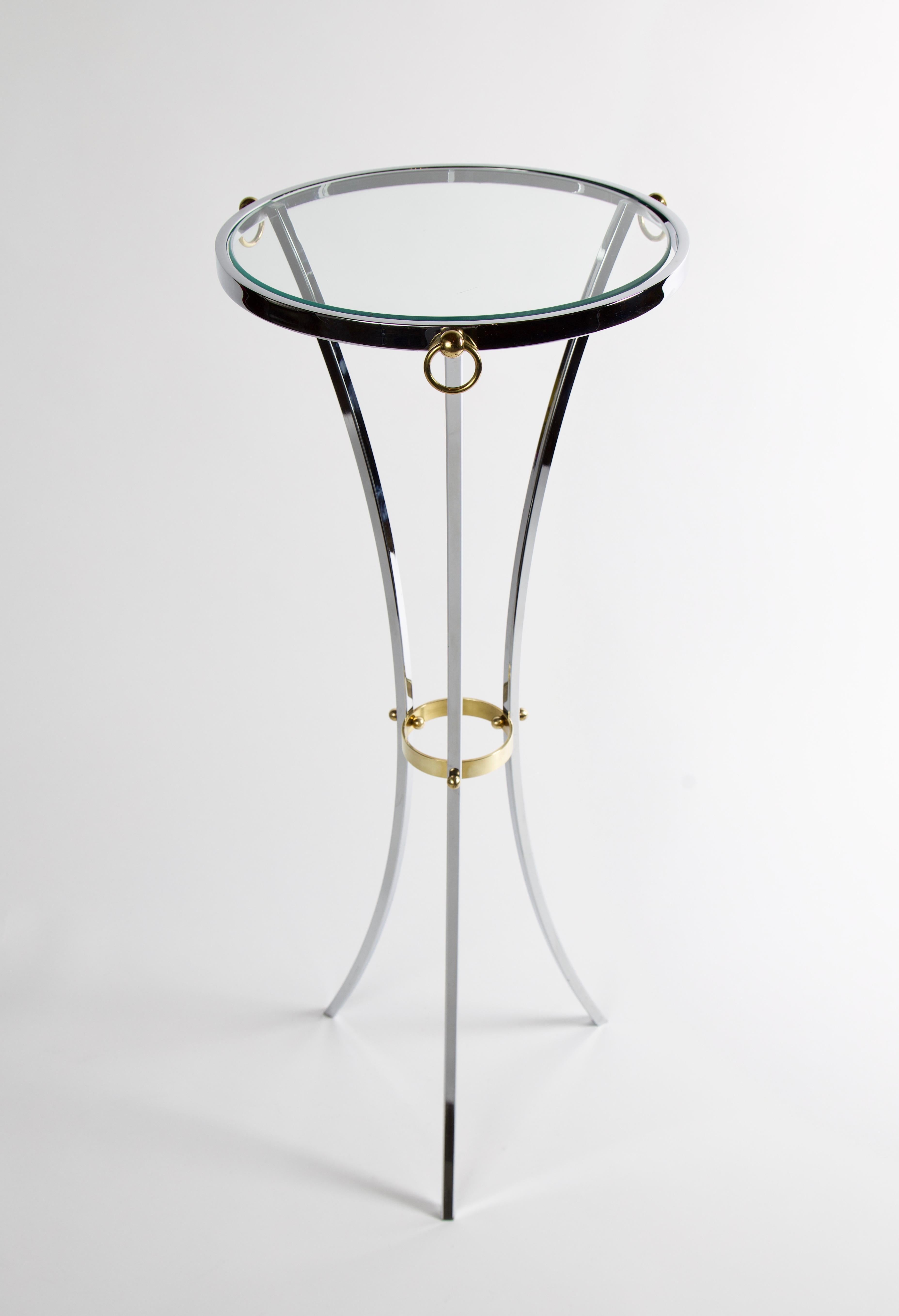 Elegant pedestal table in the manner of Maison Jansen. The table is chrome with a guéridon tripod base formed by three chromed steel arches. There are 3 brass ring mounts around perimeter of the table, as well as other brass detailing.
          