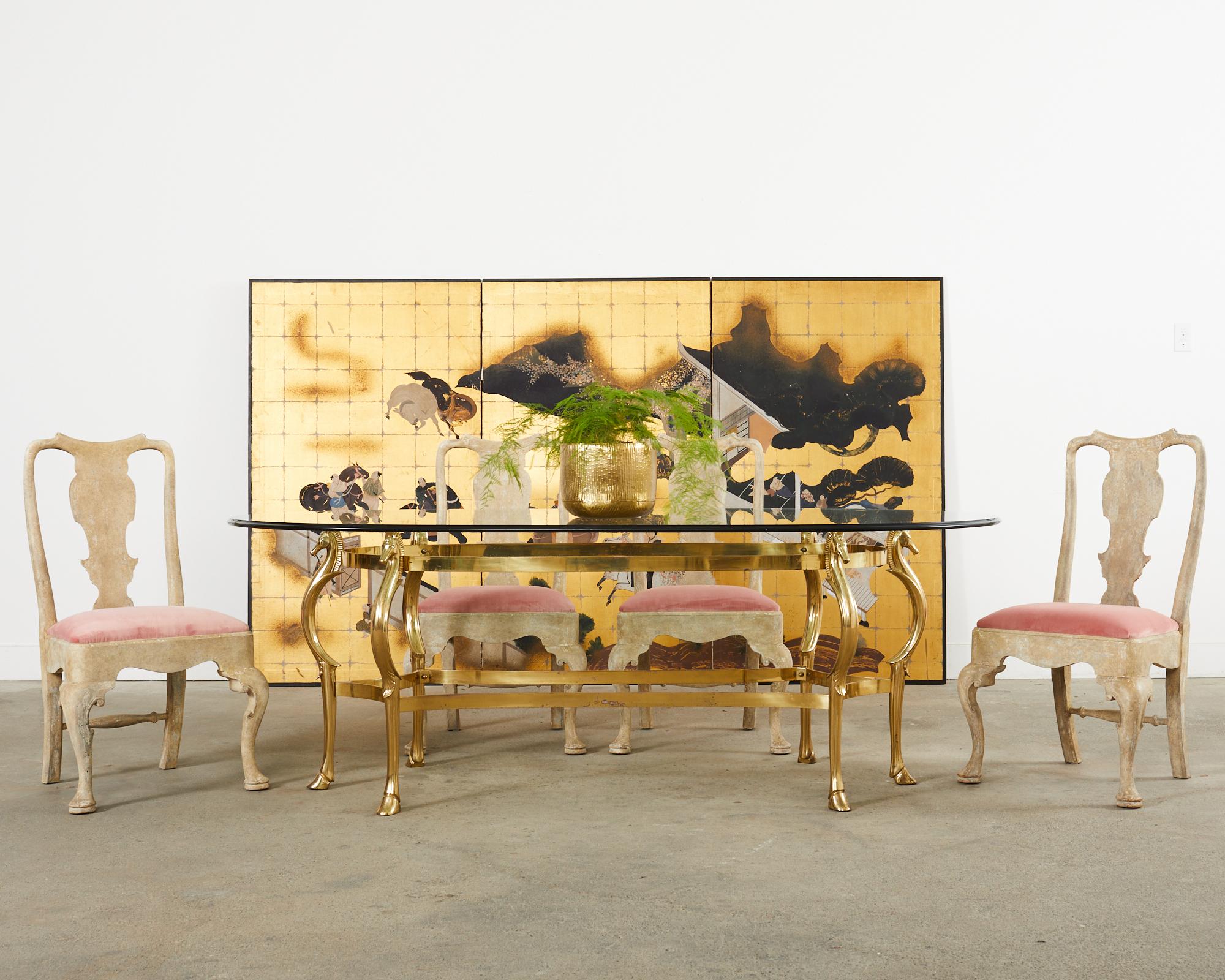Distinctive and rare Hollywood regency brass and glass dining table made in the manner and style of Maison Jansen. The large table features a solid brass base with equestrian motif horse head supports. The base has six cabriole shaped legs ending