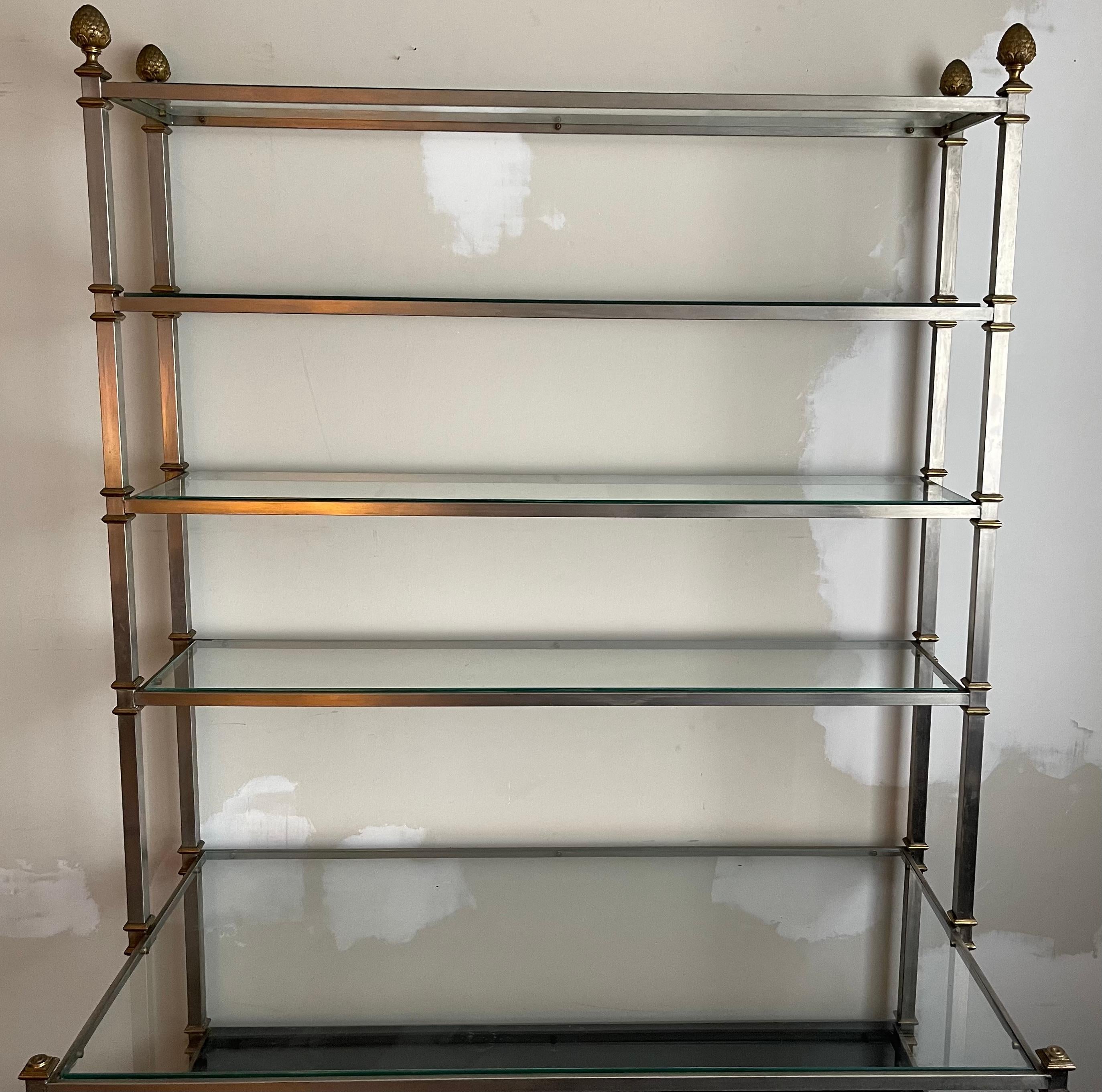 Maison Jansen style neoclassical large bookcase or etagere. Brushed steel frame with brass accents. Bottom shelves are made of black wood and upper shelves are as found clear glass. No makers mark or signature. 
Bottom shelves measure:
Middle