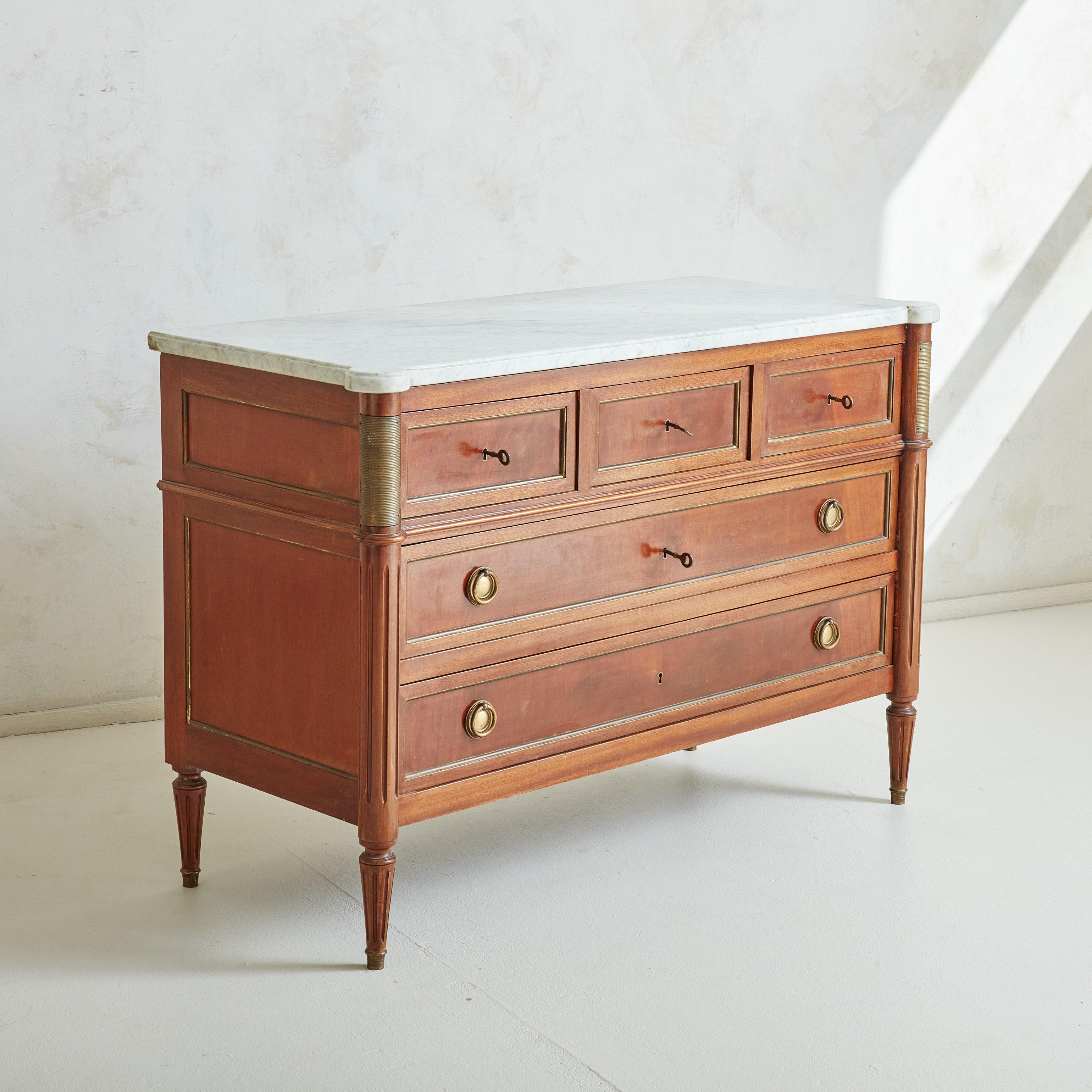 Magnifique commode XVI française des années 1950 dans le style de la Maison Jansen. Cette pièce est magnifiquement fabriquée en acajou massif et présente des colonnes décoratives, des pieds cannelés et des pieds coiffés de dorures. Un plateau en