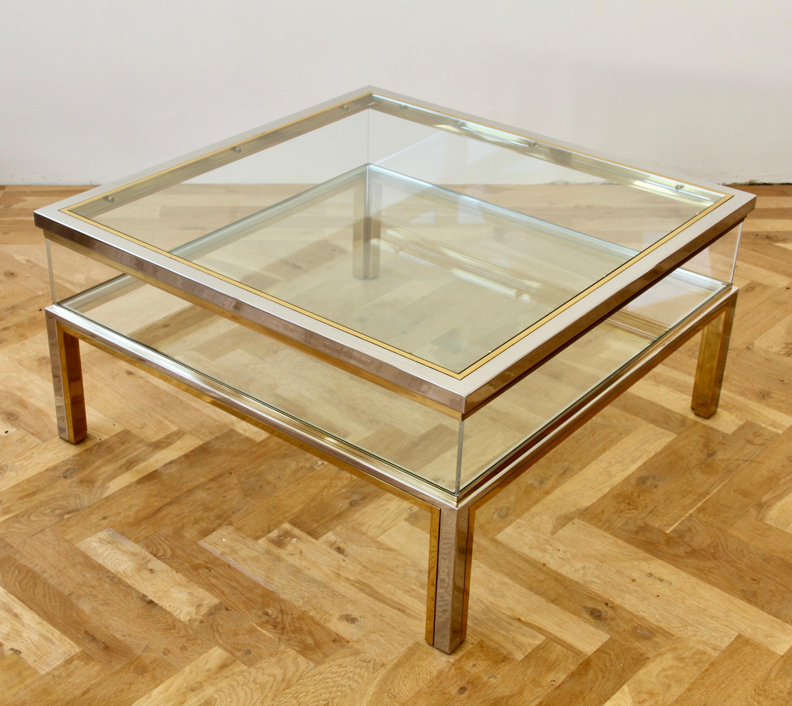 Stunning square vitrine coffee table in polished brass and chrome with sliding glass tabletop and acrylic / Lucite side walls in the style of Maison Jansen, circa 1970s. Perfect for the Hollywood Regency style enthusiast or midcentury lover