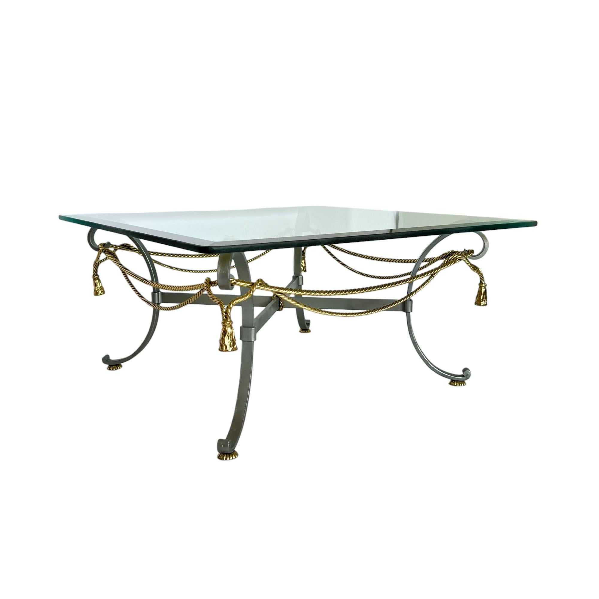 A vintage 1970's Italian Hollywood Regency style mixed metal coffee table featuring a satin finish steel frame accented with brass swag ropes, tassels and feet. It has a square beveled glass topper with rounded corners (approximately 1/2