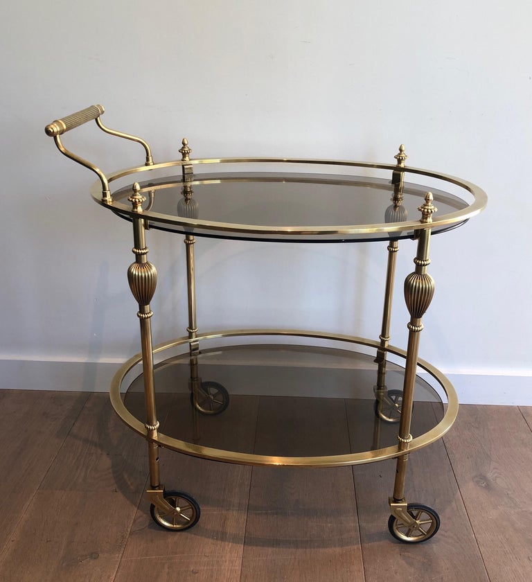 This unusual ovale bar cart is made of brass with bronzed glas shelves. This is a model attributed to famous French Designer Maison Jansen. Circa 1940.