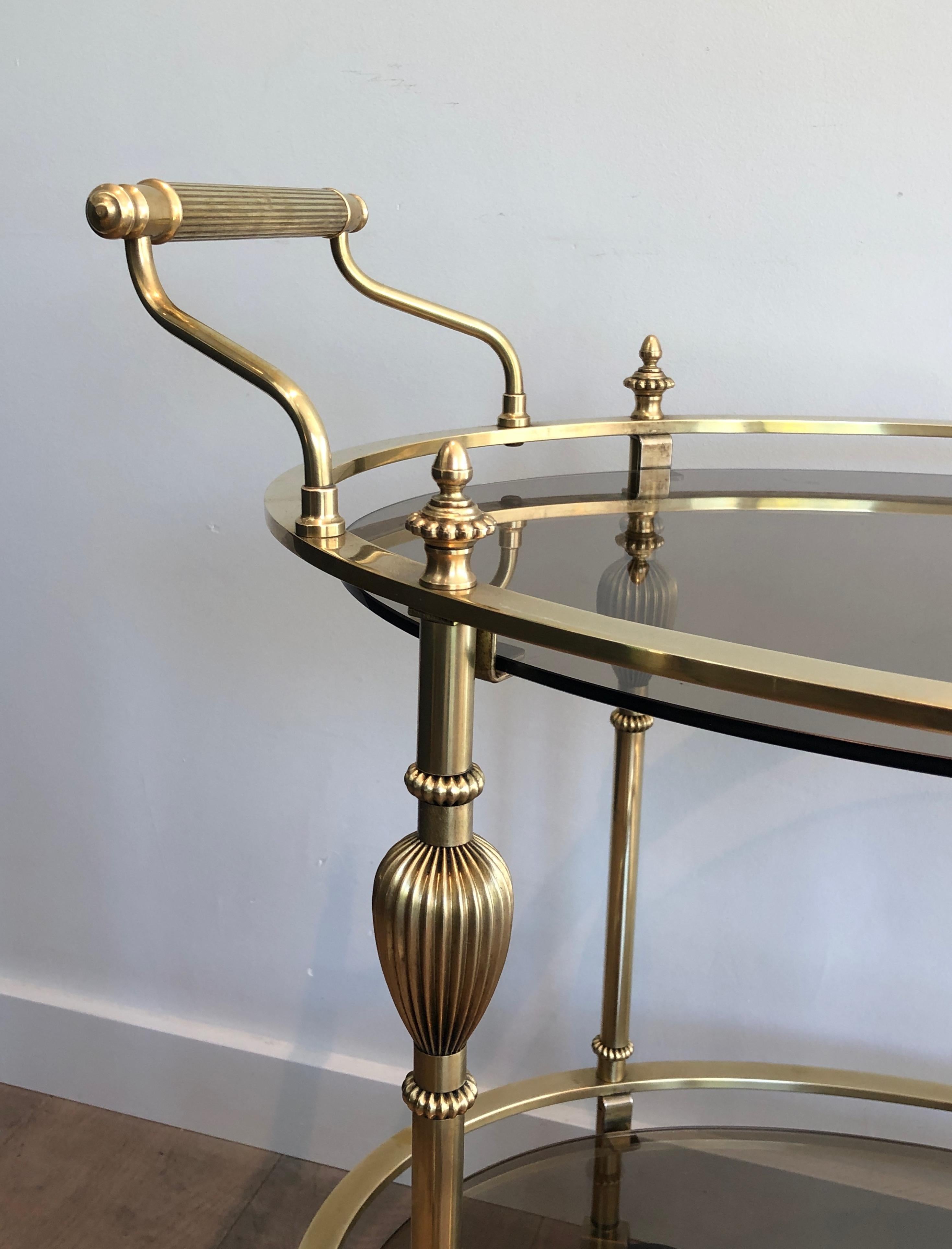 Français Chariot de bar ovale en laiton de style Maison Jansen avec étagères en verre fumé en vente