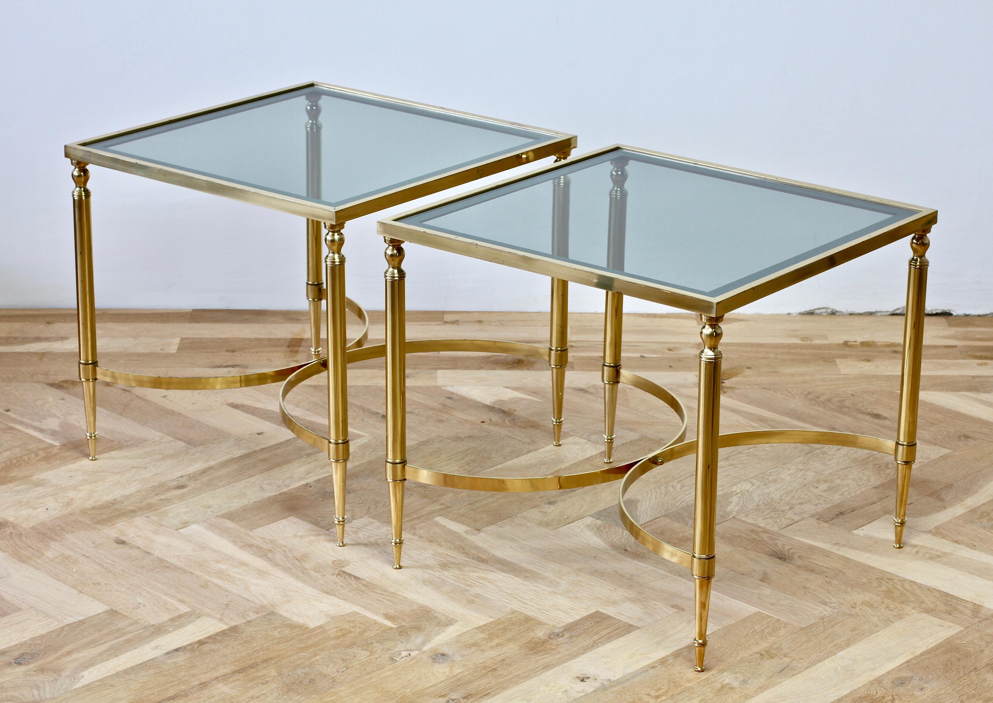 Maison Jansen style pair of 1970s French polished brass and mirrored dark, smoked / toned glass side or end tables. The table tops are simply wonderful with dark toned smoked glass and mirrored edges.

Perfect for any Hollywood Regency or midcentury