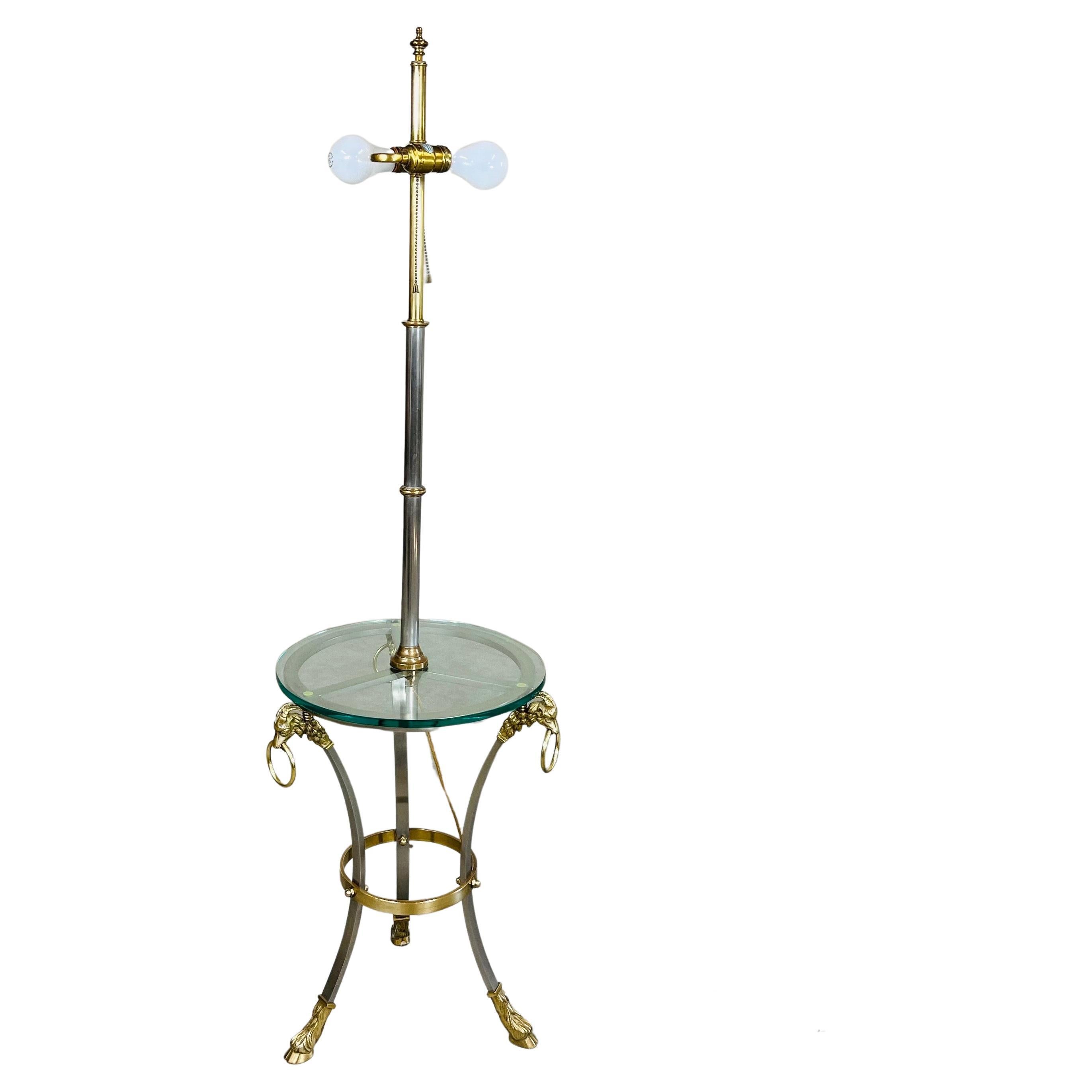 Beautiful Hollywood Regency side table floor lamp having solid brass Rams head features with matching Rams head feet, brushed nickel center stem with brass ring offsets in the manner of Maison Jansen. 
North America circa 1970. 
In outstanding