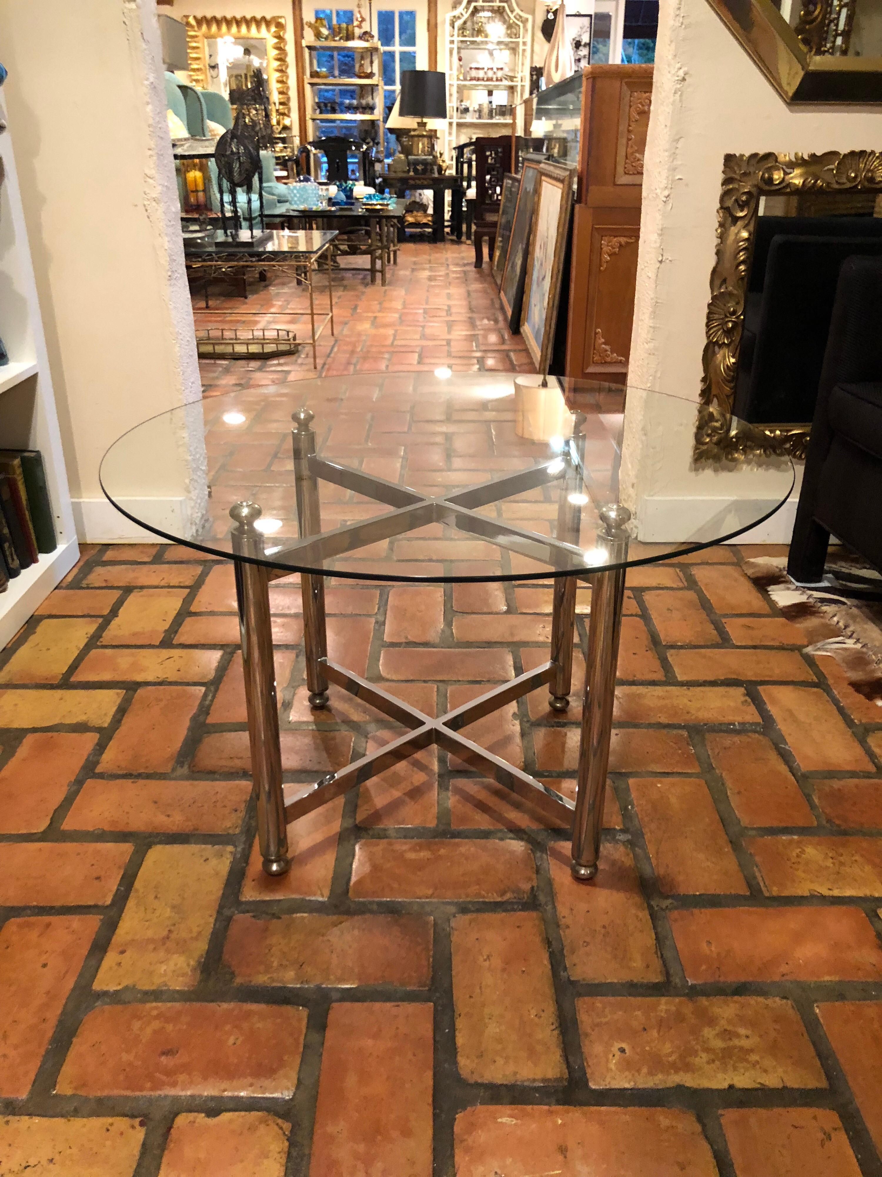 Maison Jansen style round chrome, brass and glass table. Nice round modernist, clean style. X cross stretcher design with round finial tops. Perfect for that Minimalist modern decor or Hollywood regency style home. Glass top can also be made smaller