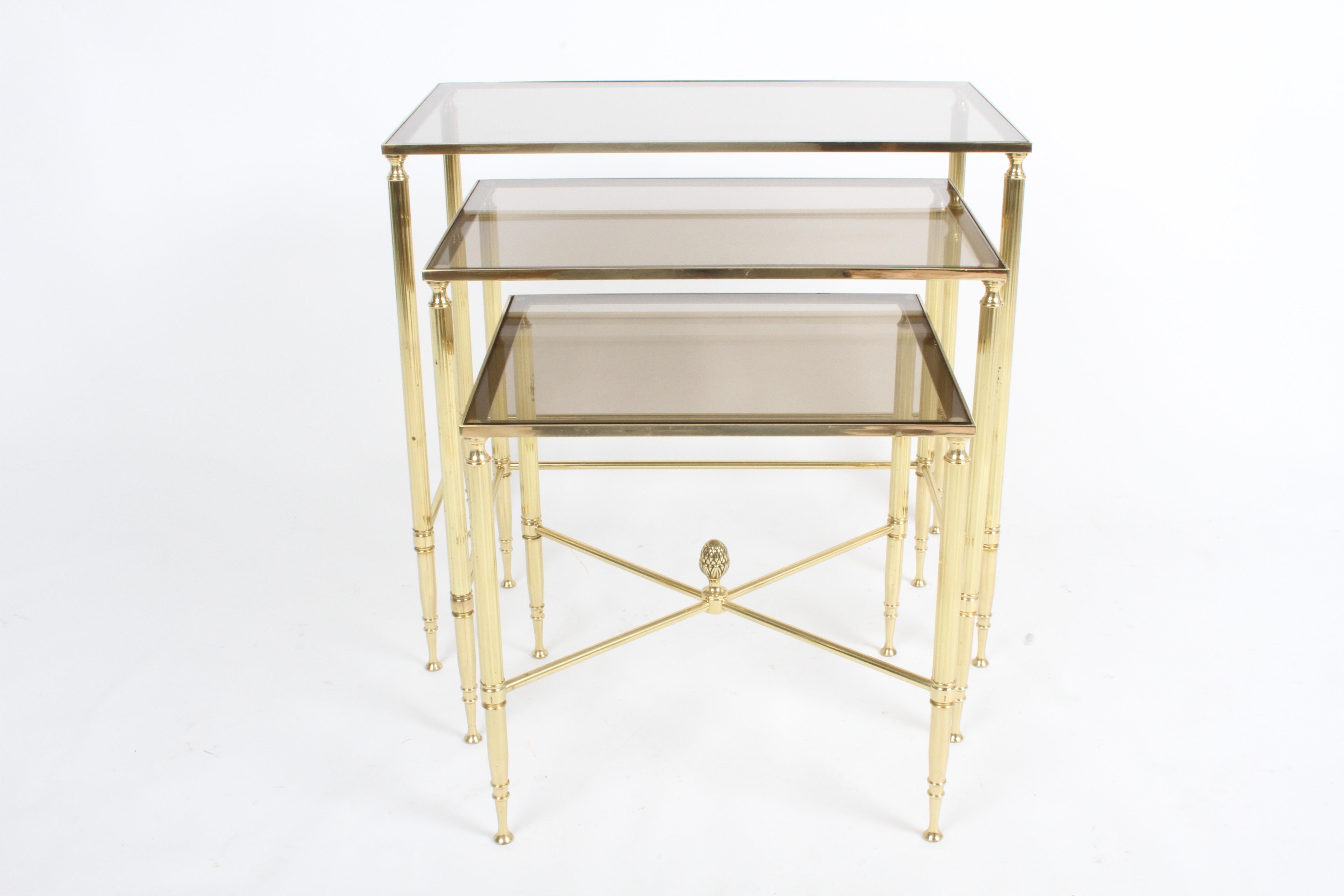 Vintage set of Maison Jansen or Neo-Classical style nesting tables with fluted bronze columns on tapered legs and bronzed colored glass tops. In fine condition with light patina to brass. 

Measures: Large 13.94