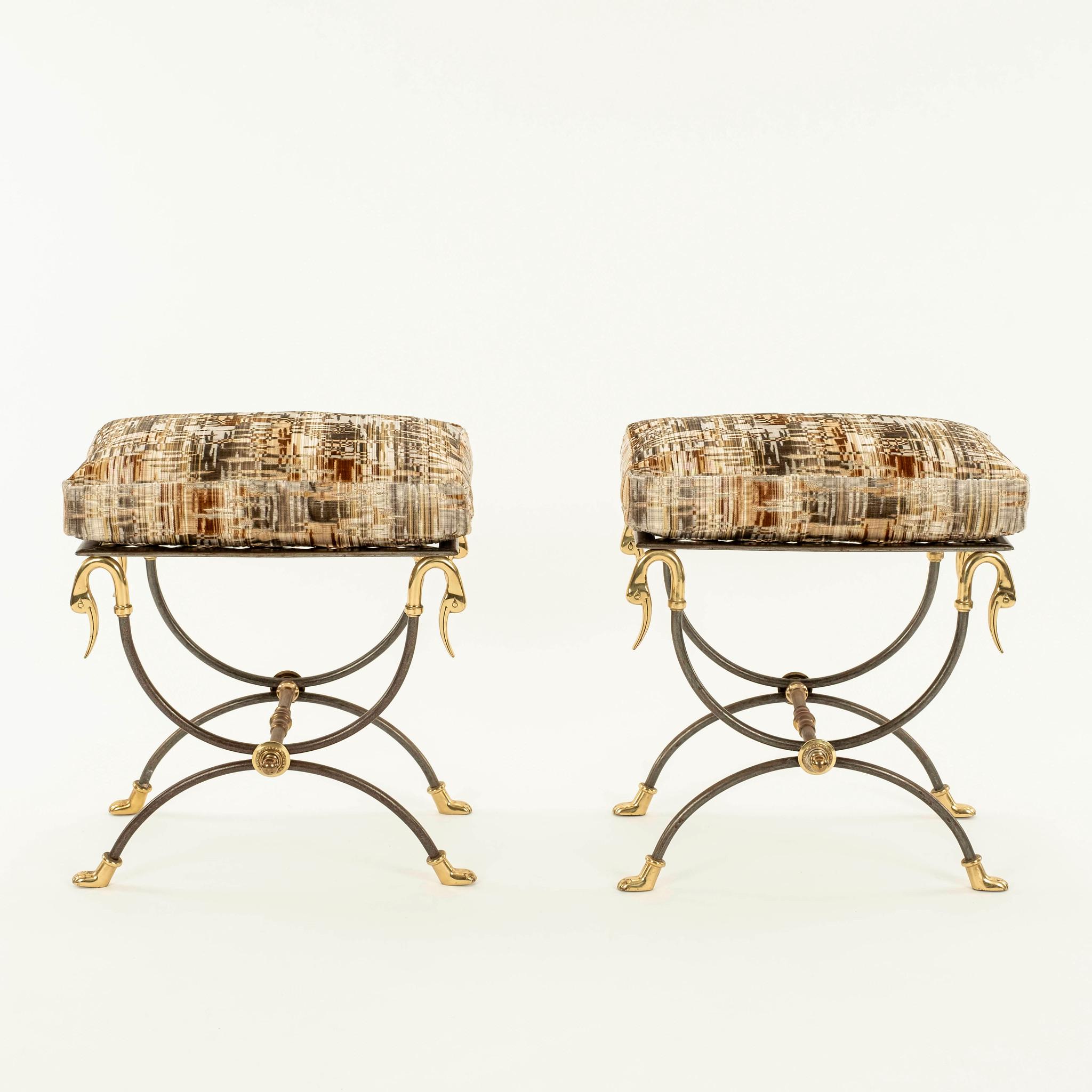 Pair of 1950s French Neoclassical style curule steel ottomans featuring brass swan head mounts, stretcher and lion paw feet . Seats are topped with custom loose feather down box cushions in a gilded platinum colored cut velvet geometric striated