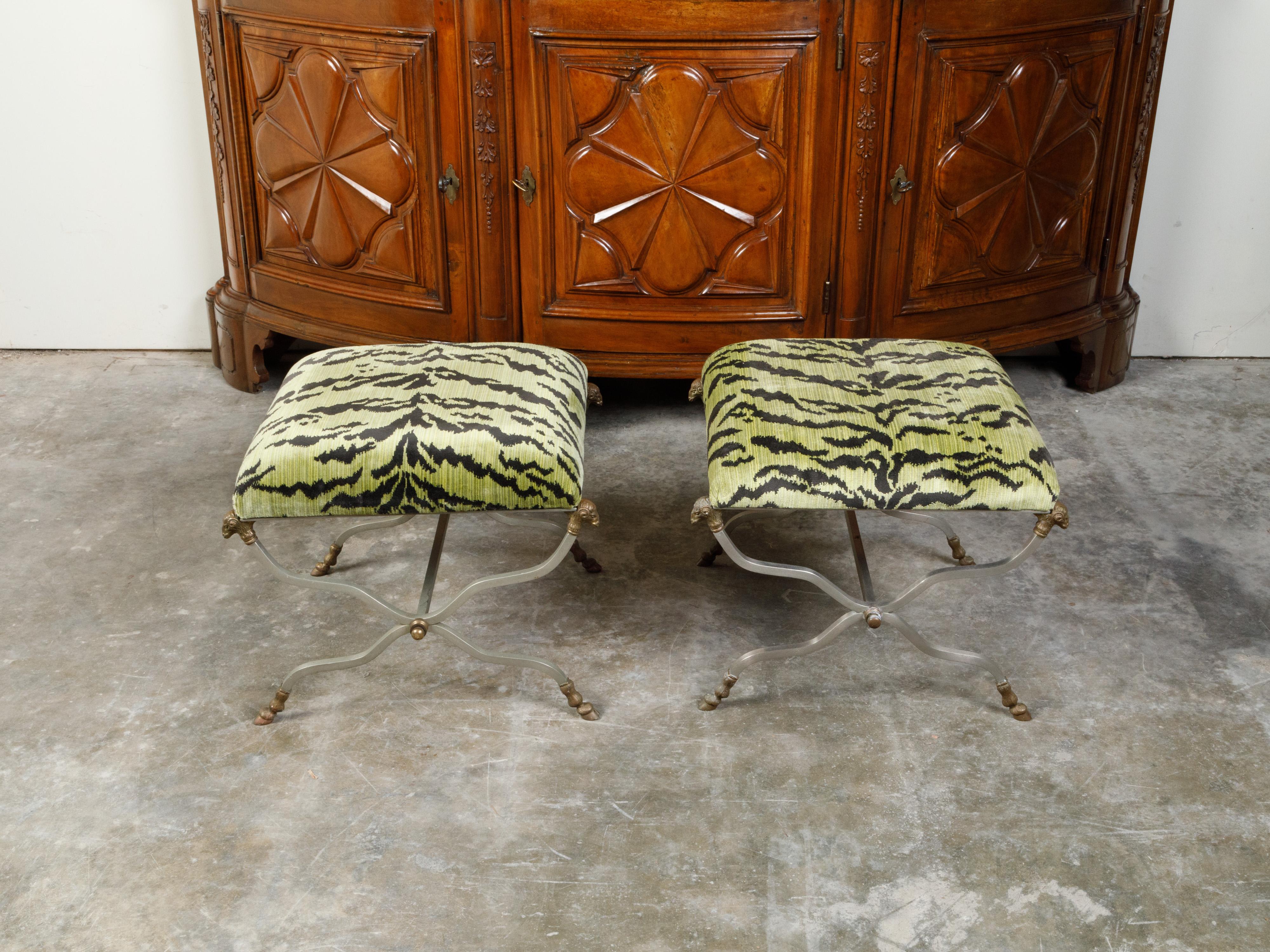 A pair of Italian Maison Jansen style steel and brass stools from the mid-20th century, with rams' heads and faux tiger upholstered seats. Created in Italy during the midcentury period, each of this pair of stools features a rectangular light green