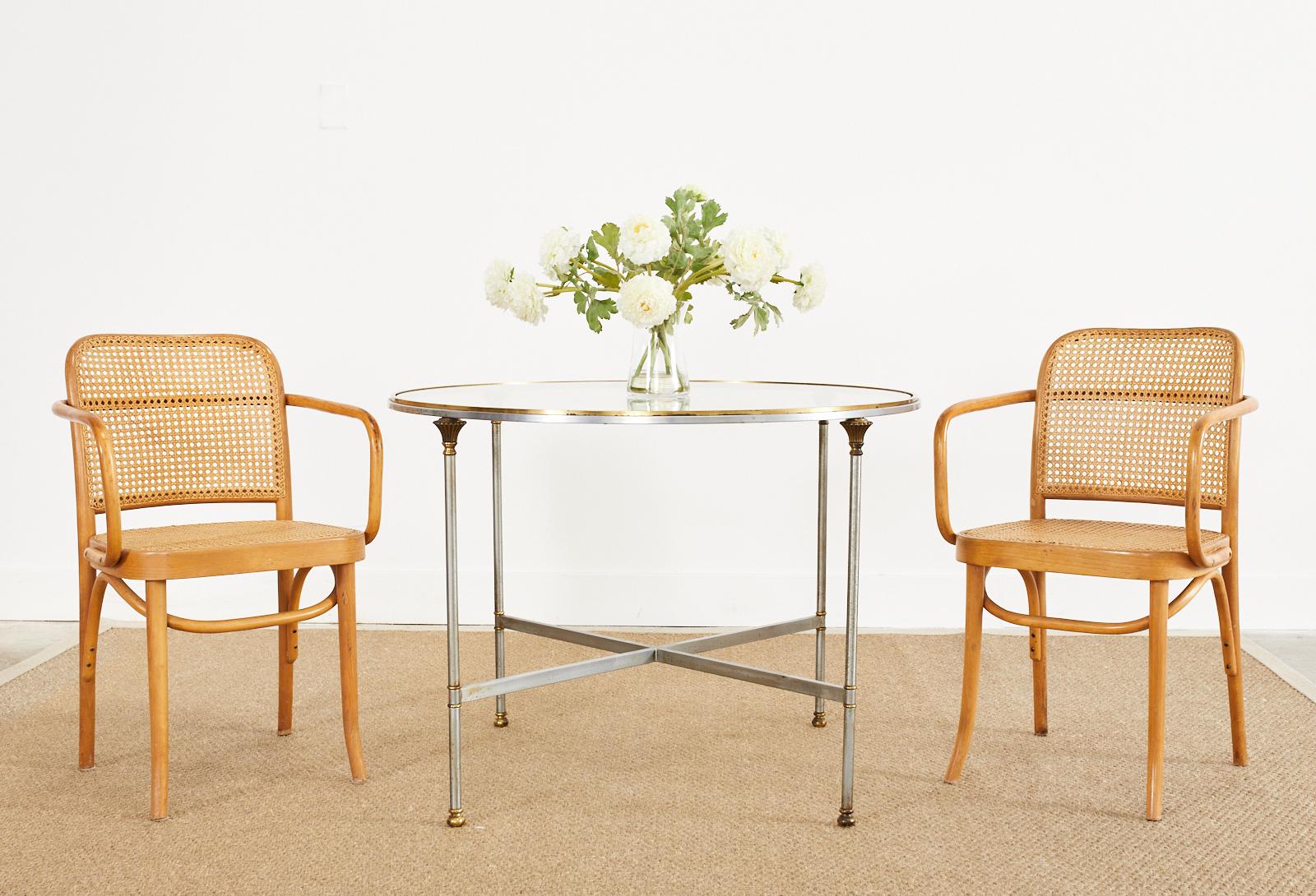 Opulent steel and bronze round center table or dining table made in the manner and style of Maison Jansen. The table features four column style legs with bronze fluted capitals. The legs are conjoined in the middle with cross stretchers and end with