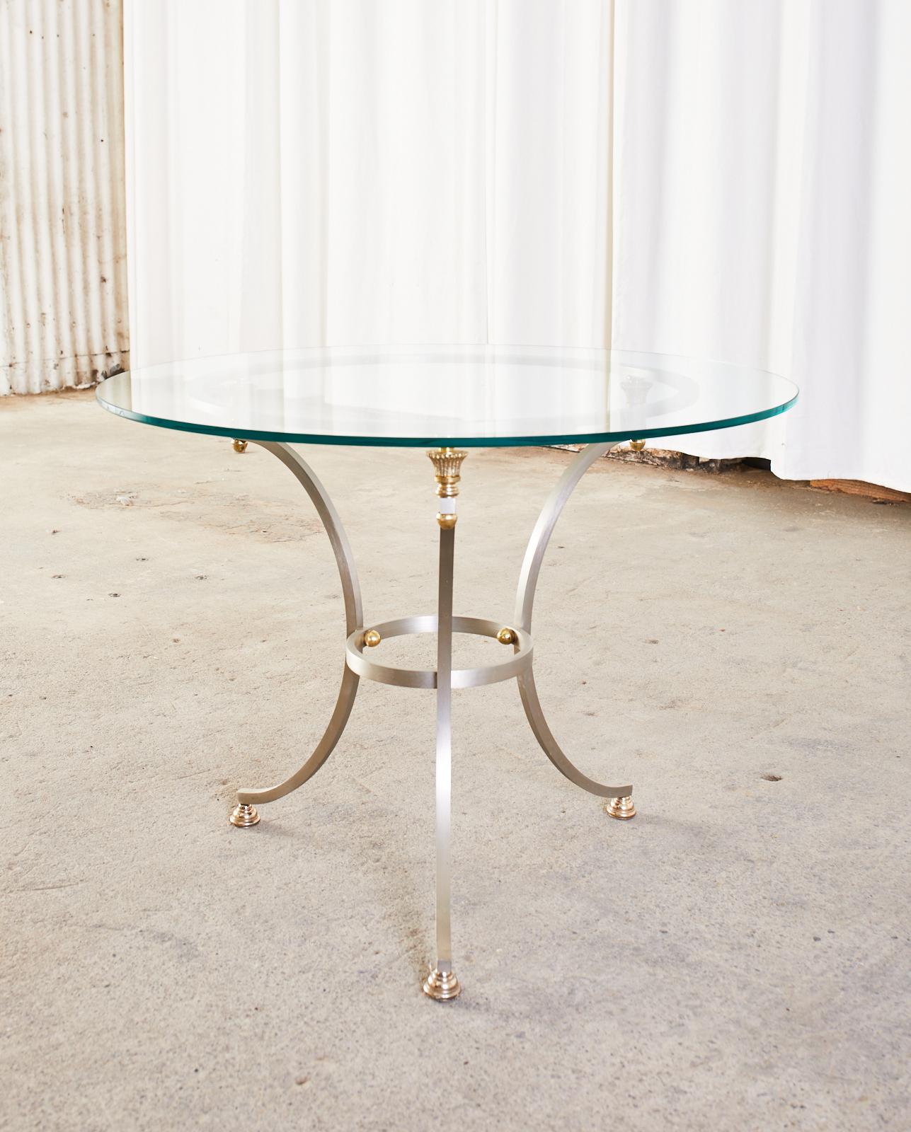 Attractive brushed steel and bronzed metal gueridon style drinks table made in the neoclassical Maison Jansen manner constructed from three gracefully curved legs conjoined by round stretchers. The tripod frame is decorated with bronze toned finials