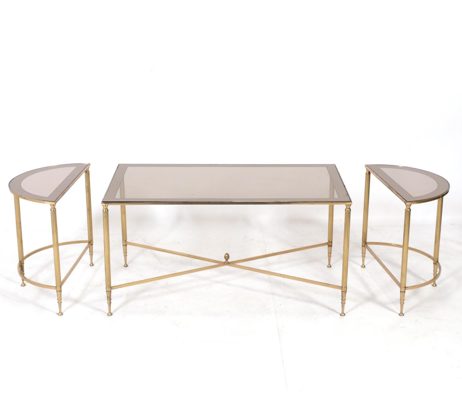 Elegant neoclassical three piece brass coffee table, in the style of Maison Jansen, France, circa 1950s. Constructed of brass or bronze with mirrored edge bronze color glass tops. The three pieces can be used together to form an elegant infinity