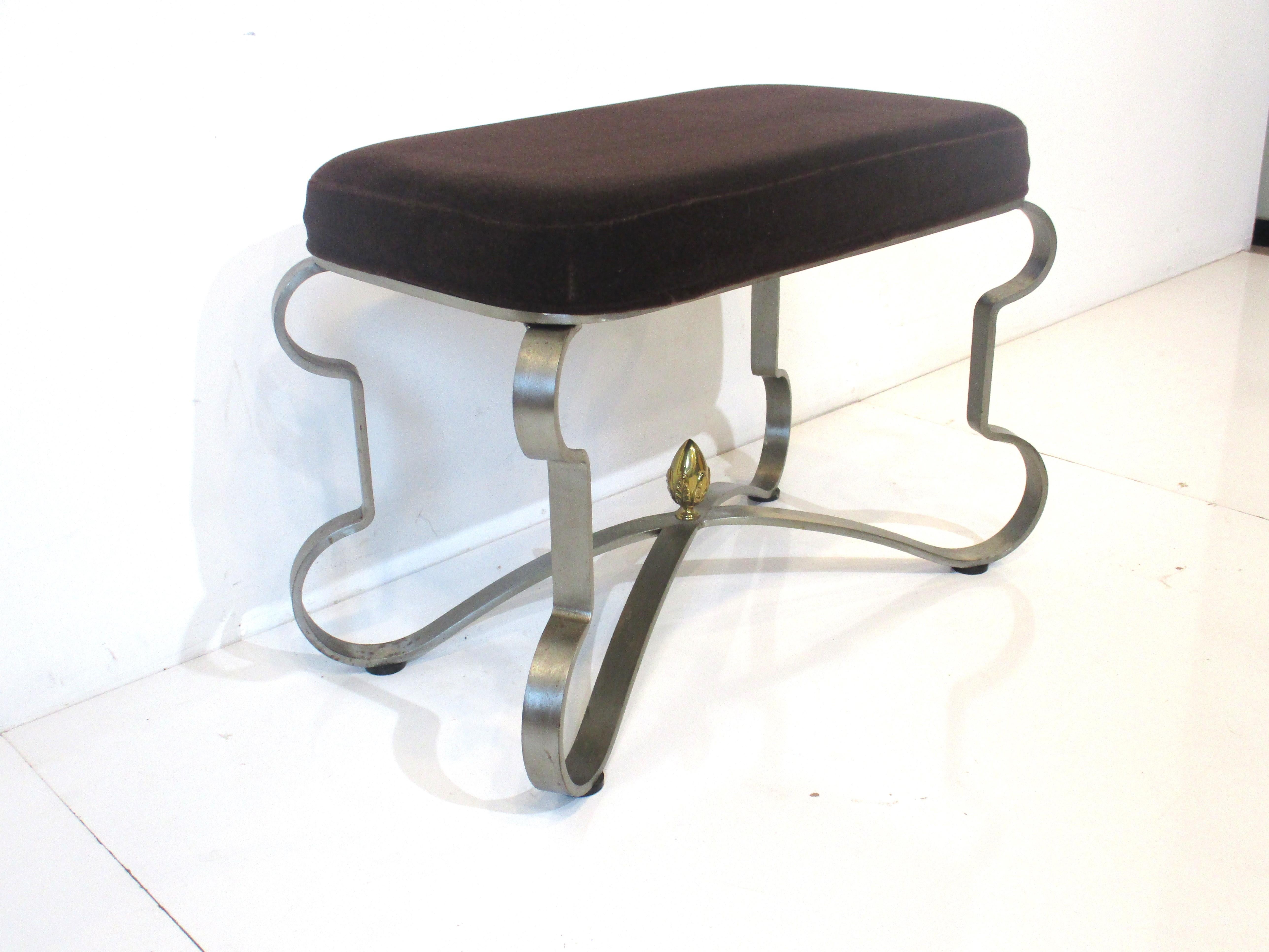 A sculptural banded steel based stool with dark brown velvet upholstered seat cushion and to the center a gold toned Fleur-de-lis type detail. Manufactured and designed in the manner of Maison Jansen, very well made.