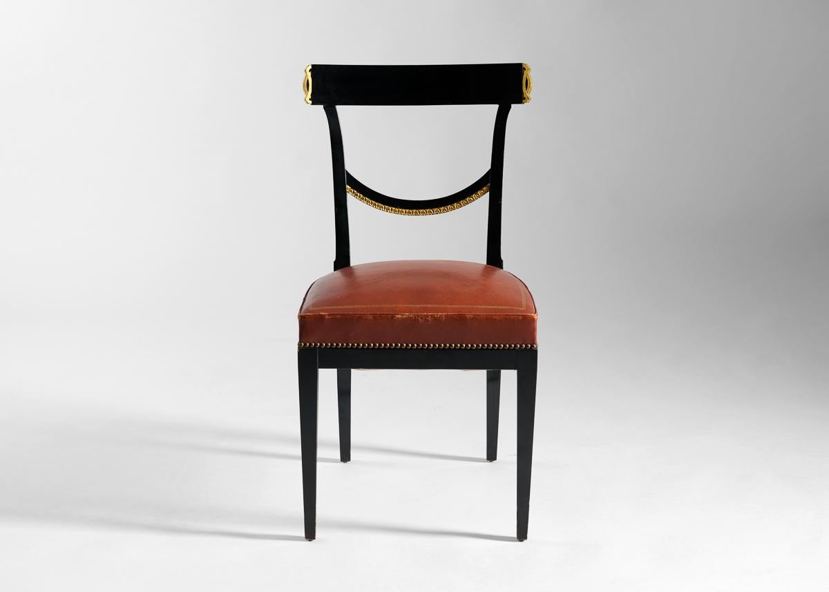 These fourteen lacquered dining chairs possess wide, comfortable seats, but are remarkable for the classical form of their hand-carved backrests—a ribbon of gilt wood spanning each, as if draped from one side to the other. 

For the better part of a