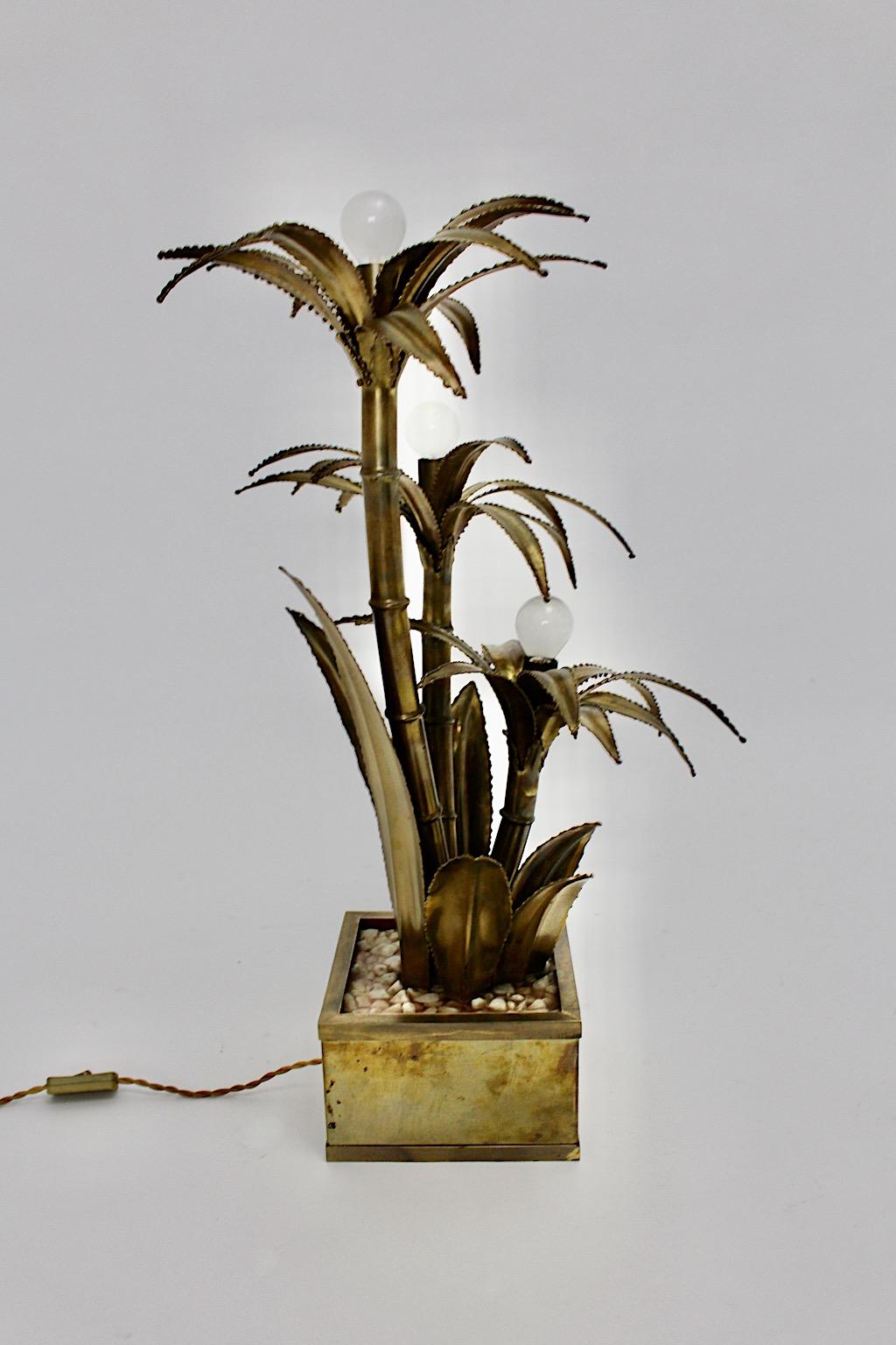 Maison Jansen vintage brass table lamp, which was designed and executed 1970s France.
While the table lamp shows a beautiful shape formed like a palm tree with leaves, the brass base features small marble stones cast in lucite.
The table lamp was
