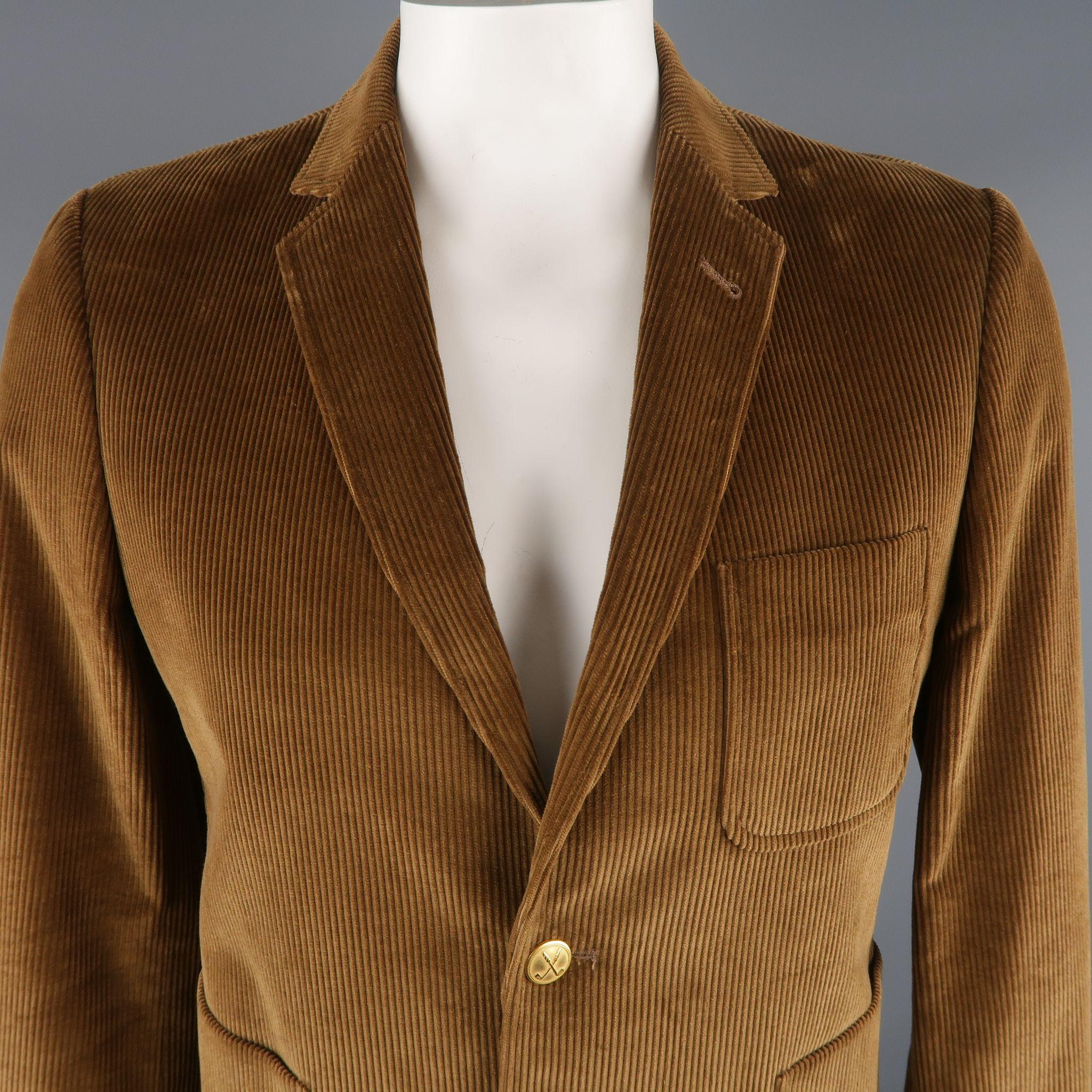 MAISON KITSUNE Sport Coat comes in a light brown tone in a solid corduroy cotton material, with a notch lapel, patch pockets, embossed gold tones metal buttons, 2 button closure and single breasted. Minor wear at one of the closure buttons. With 2
