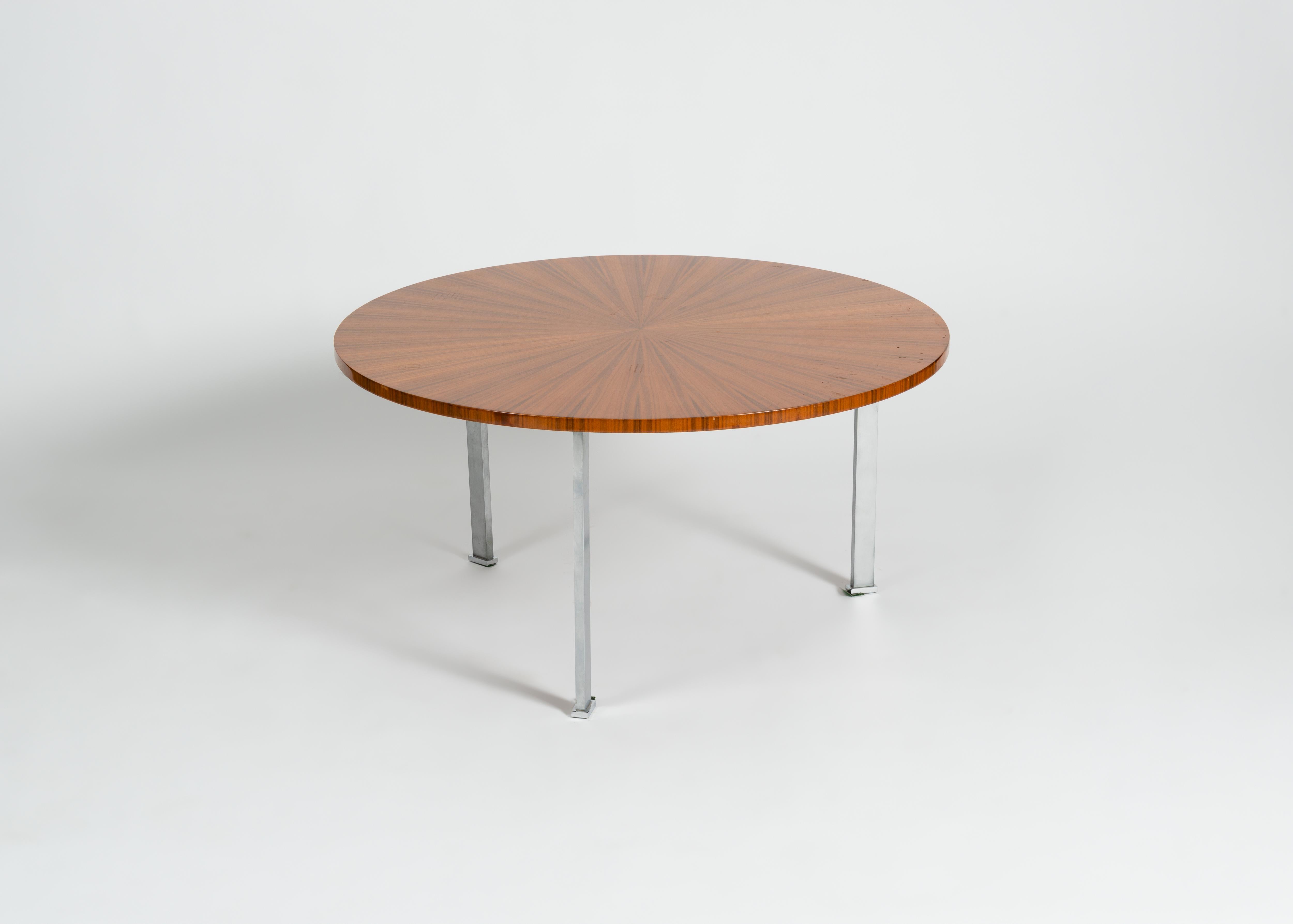 Cette belle table basse de la Maison Leleu est un bel exemple de la production de la firme dans les années 1960 : une élégante base tripode en aluminium surmontée d'une pièce d'acajou parfaitement circulaire, dont le grain rayonne à partir de son