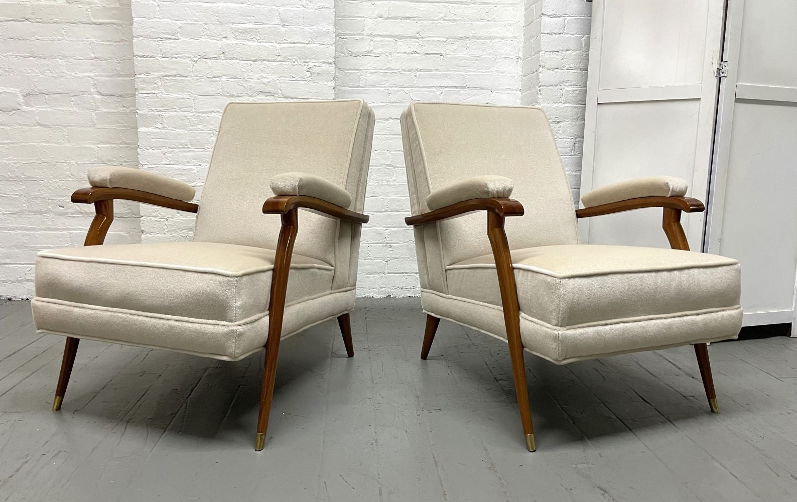 Pair of French Art Deco lounge chairs in the style of Maison Leleu. The chairs have birch frames, padded arms, and bronze sabots. Upholstered in mohair fabric.