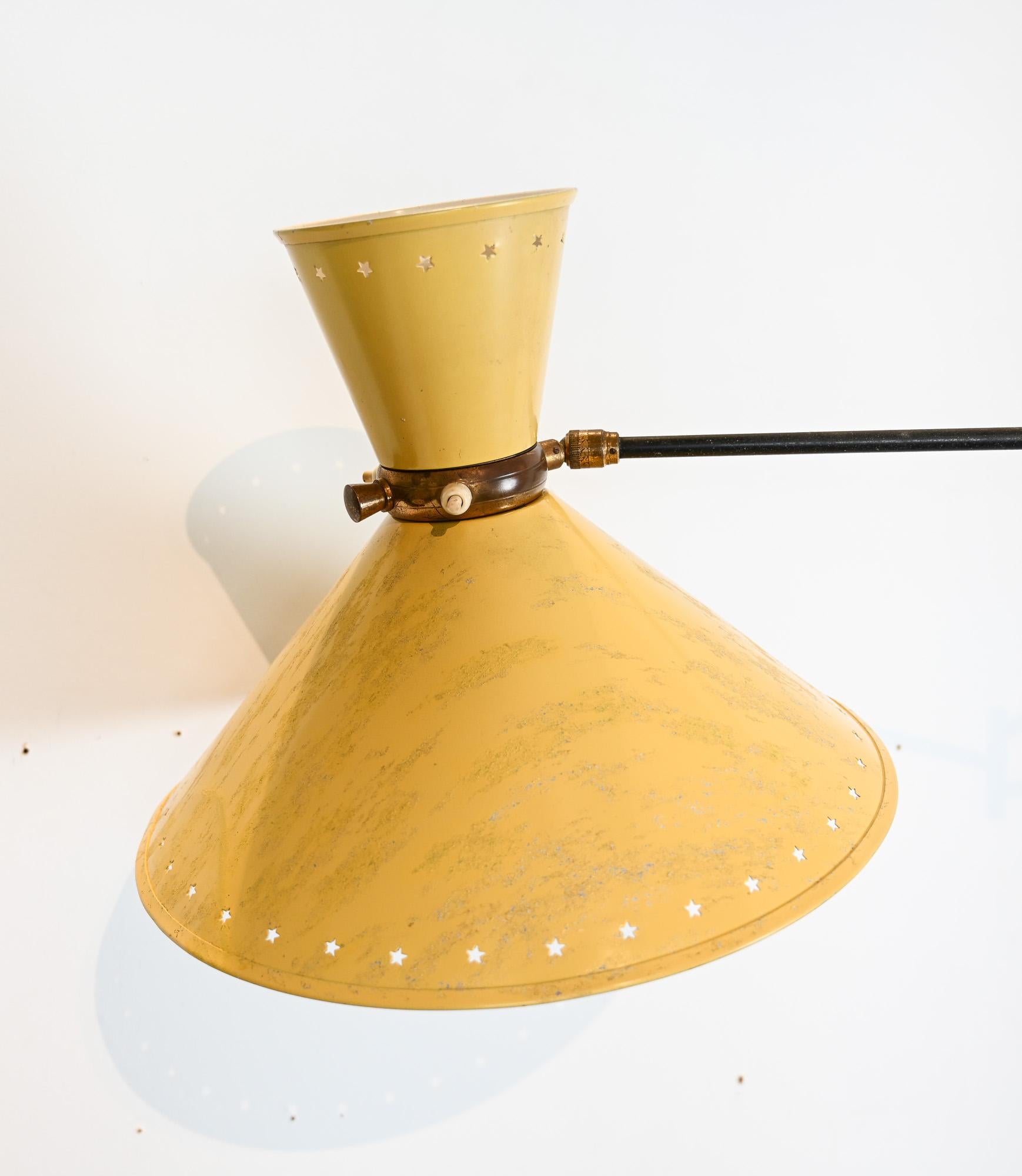 Raro aplique articulado atribuido a Maison Lunel, Francia, hacia la década de 1950.

Este elegante diseño presenta una pantalla bicónica (diábolo) lacada en amarillo con perforaciones en forma de estrella alrededor del borde, un detalle distintivo