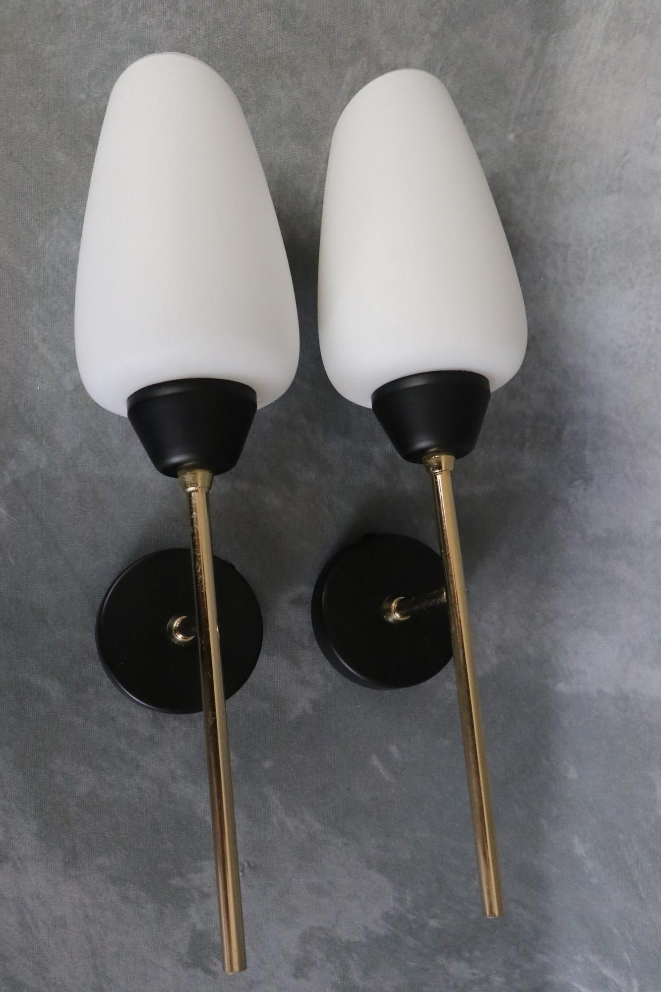 Maison Lunel - pair of Mid-Century Modern wall lights - 1950s France.

Very nice pair of sconces in the 50's design. 
They are all in contrast: the luminous and milky whiteness of the opaline is opposed to the dark base of the blackened brass,