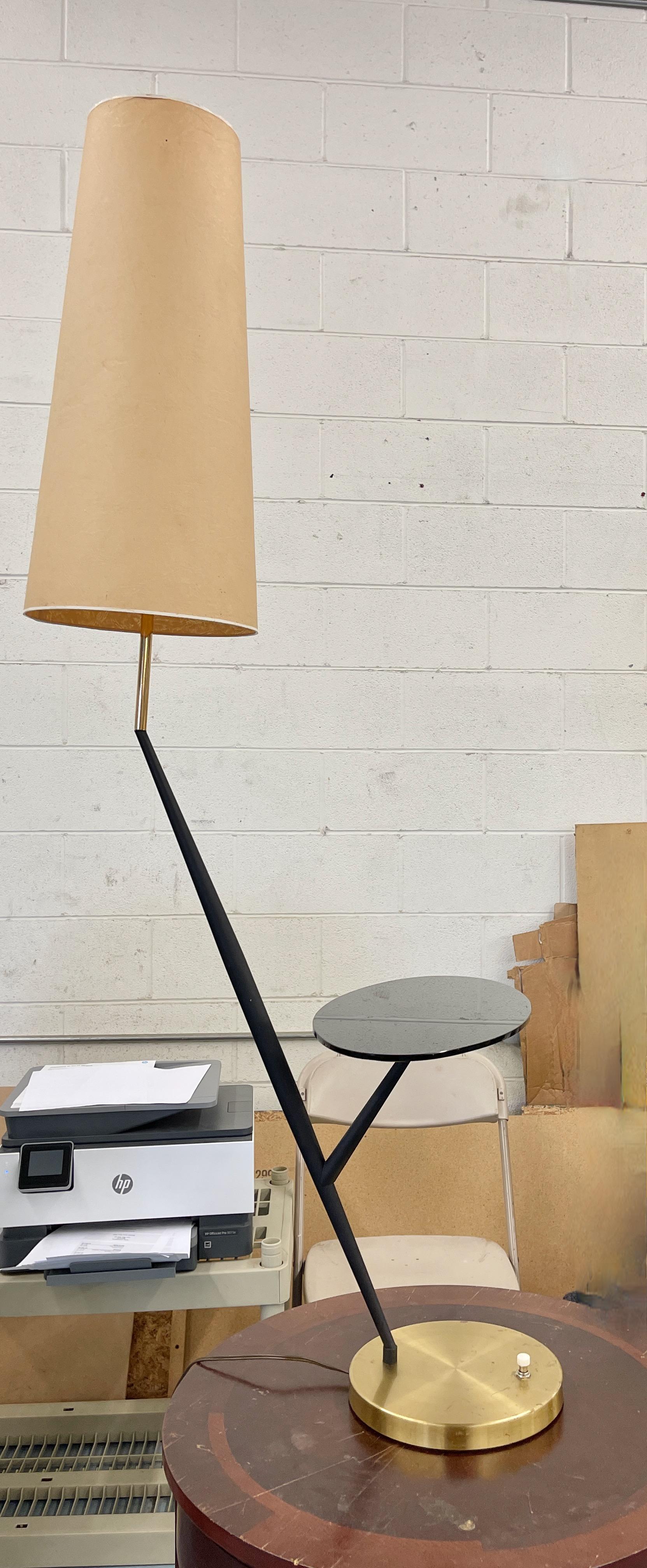 French early 1960’s sculptural floor (or table) lamp with a sculptural matte black elongated double tapered metal stem cocked at ~75 degree angle and having an 8 inch attenuated branch supporting an elliptical oval plateau of polished black